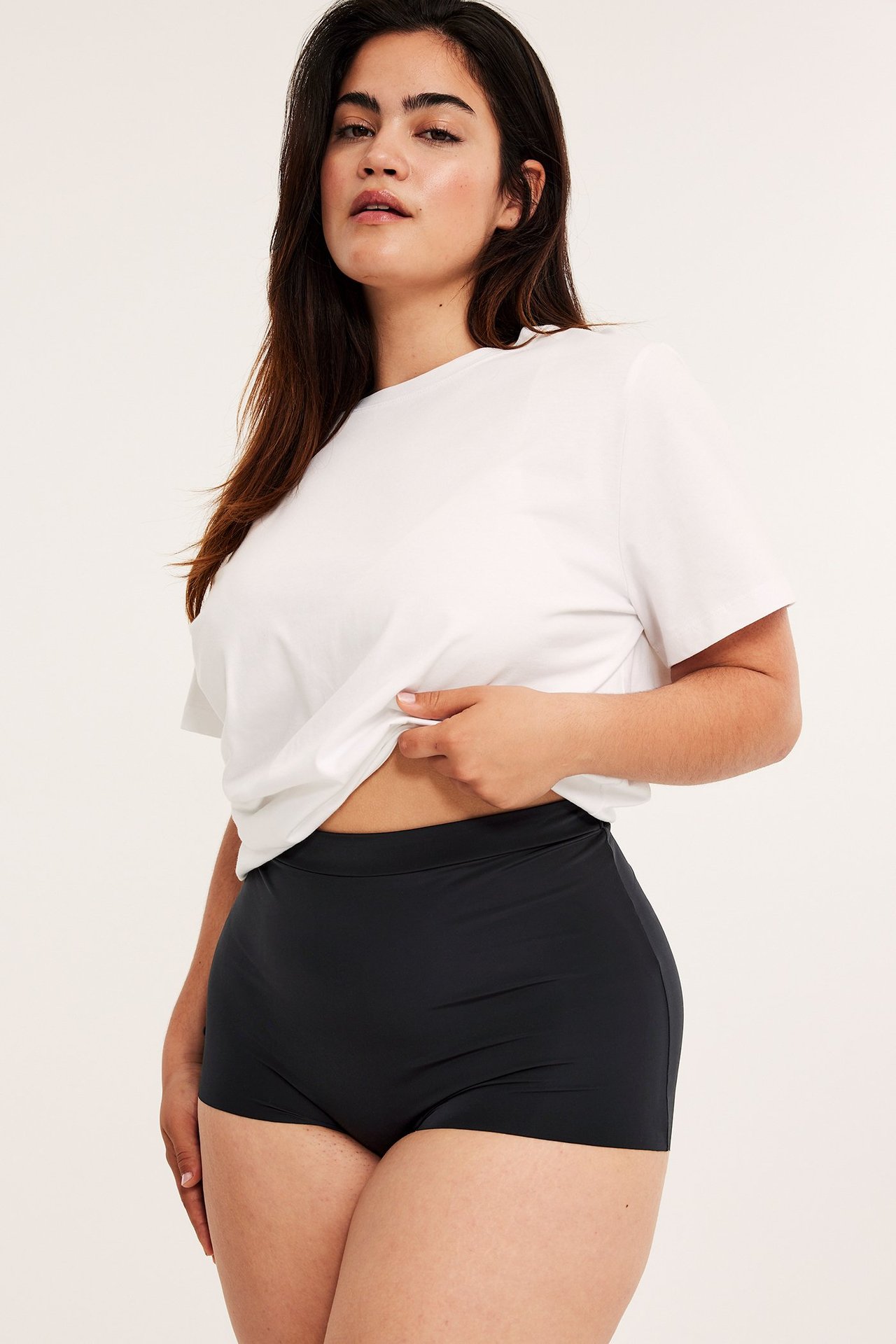 Frontbilde av kvinne i svarte mikro-boxertruser med en hvit t-skjorte.