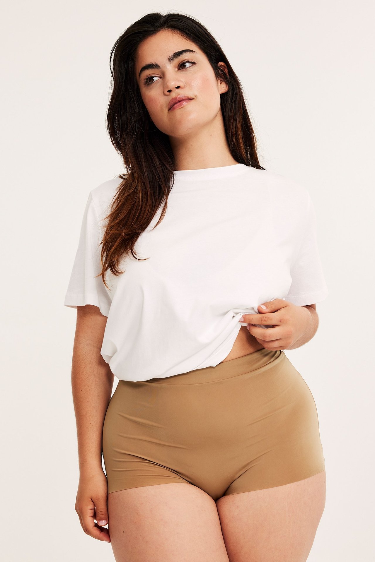 Forfra: Kvinne i brune mikro-boxertruser med sømløs benåpning og en hvit t-skjorte.