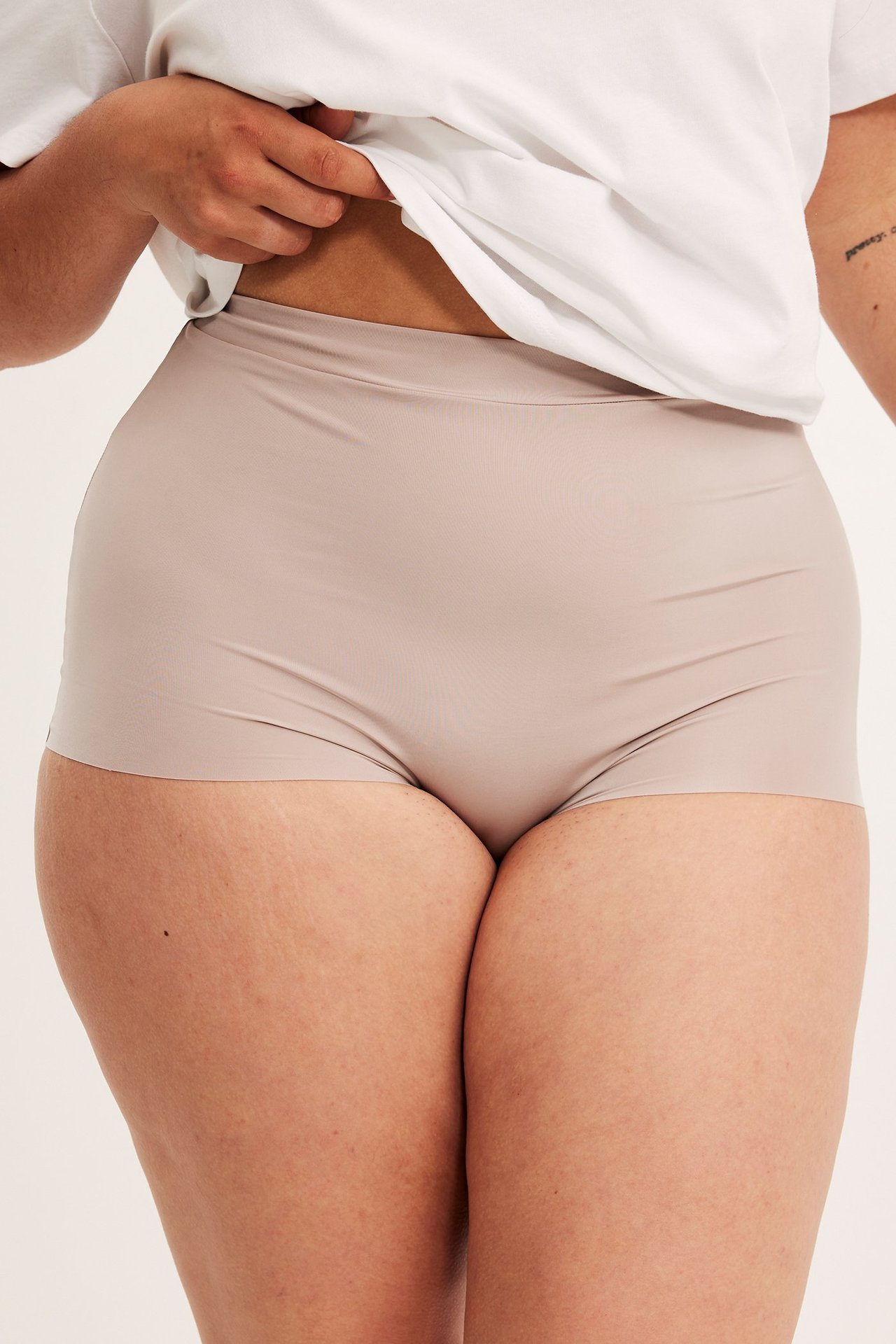 Framifrån, kvinna i ljusrosa microfiber boxertrosor med resår i midjan och uppdragen vit t-shirt.