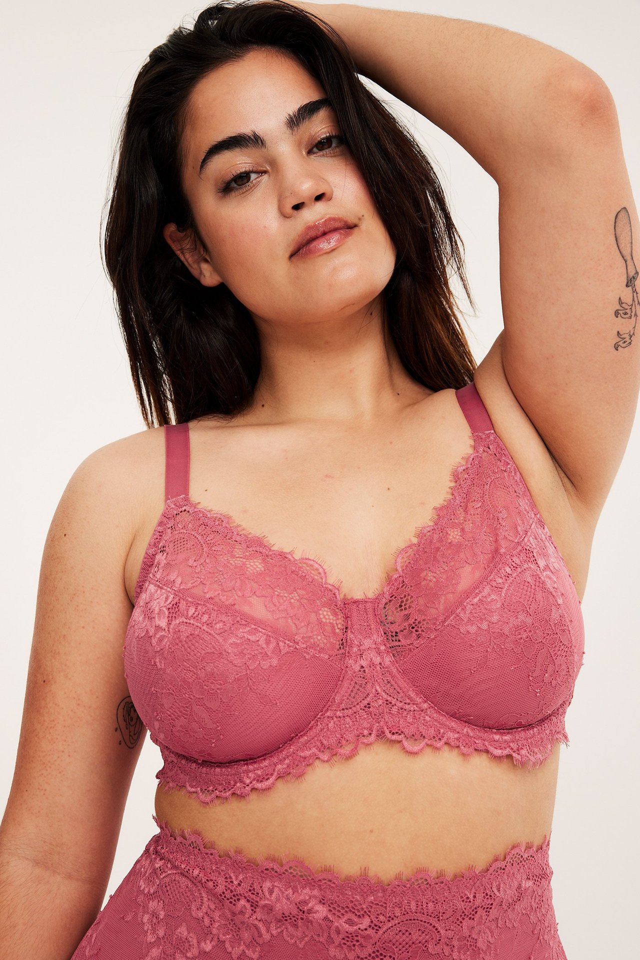 Forfra: Kvinne i en rosafarget uvattert bøyle-BH i blonde og matchende blondeunderdel.