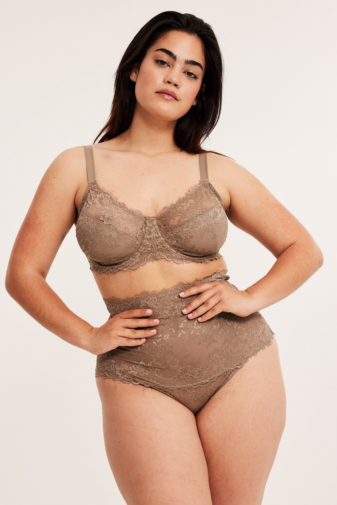 Framifrån, kvinna i beige ovadderad bygel-bh i spets med matchande högmidjade trosor.