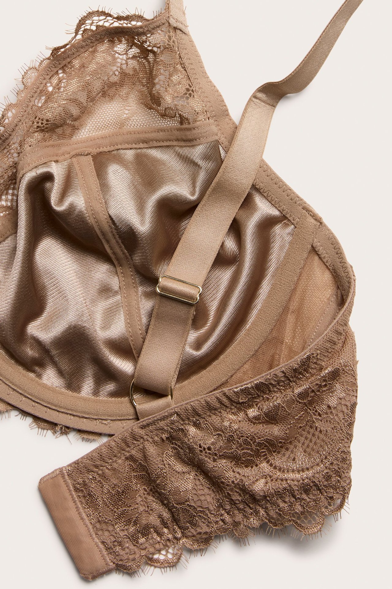 Zbliżenie beżowego, nieusztywnianego biustonosza z fiszbinami, koronką i satynowym podszyciem.