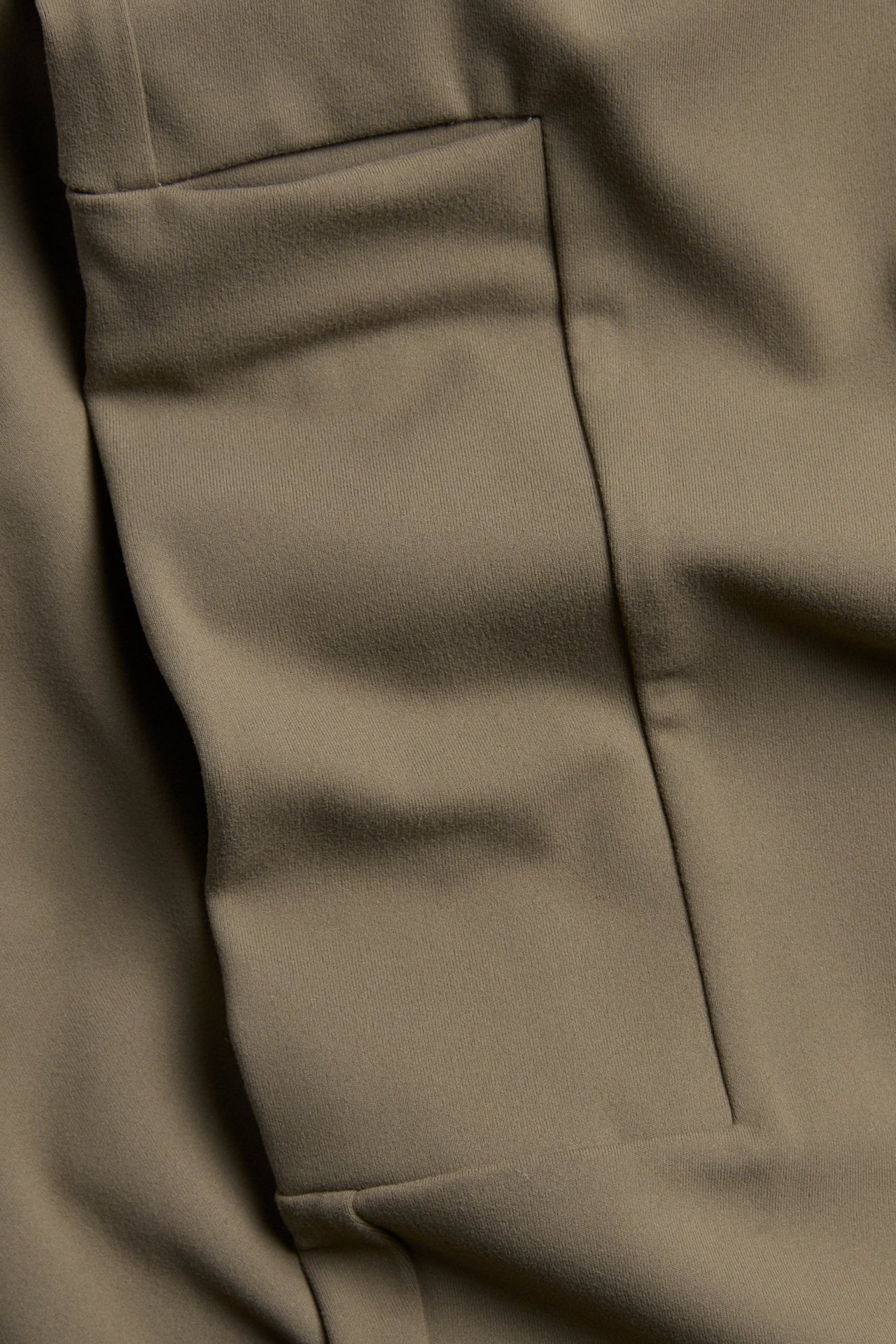 Zbliżenie brązowych legginsów treningowych z miękką powierzchnią i kieszenią na nogawce.