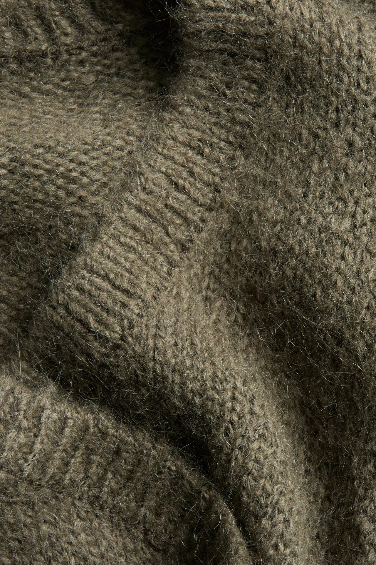 Zbliżenie na ciemnozielony sweter z mieszanki wełny z subtelnym wzorem w paski.