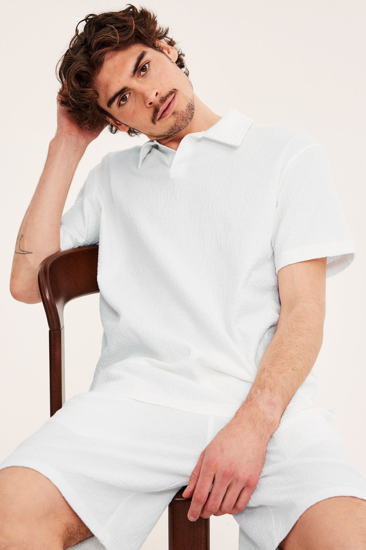 Edestä, mies yllään luonnonvalkoinen strukturoitu lyhythihainen pikeepaita ja yhteensopivat shortsit.