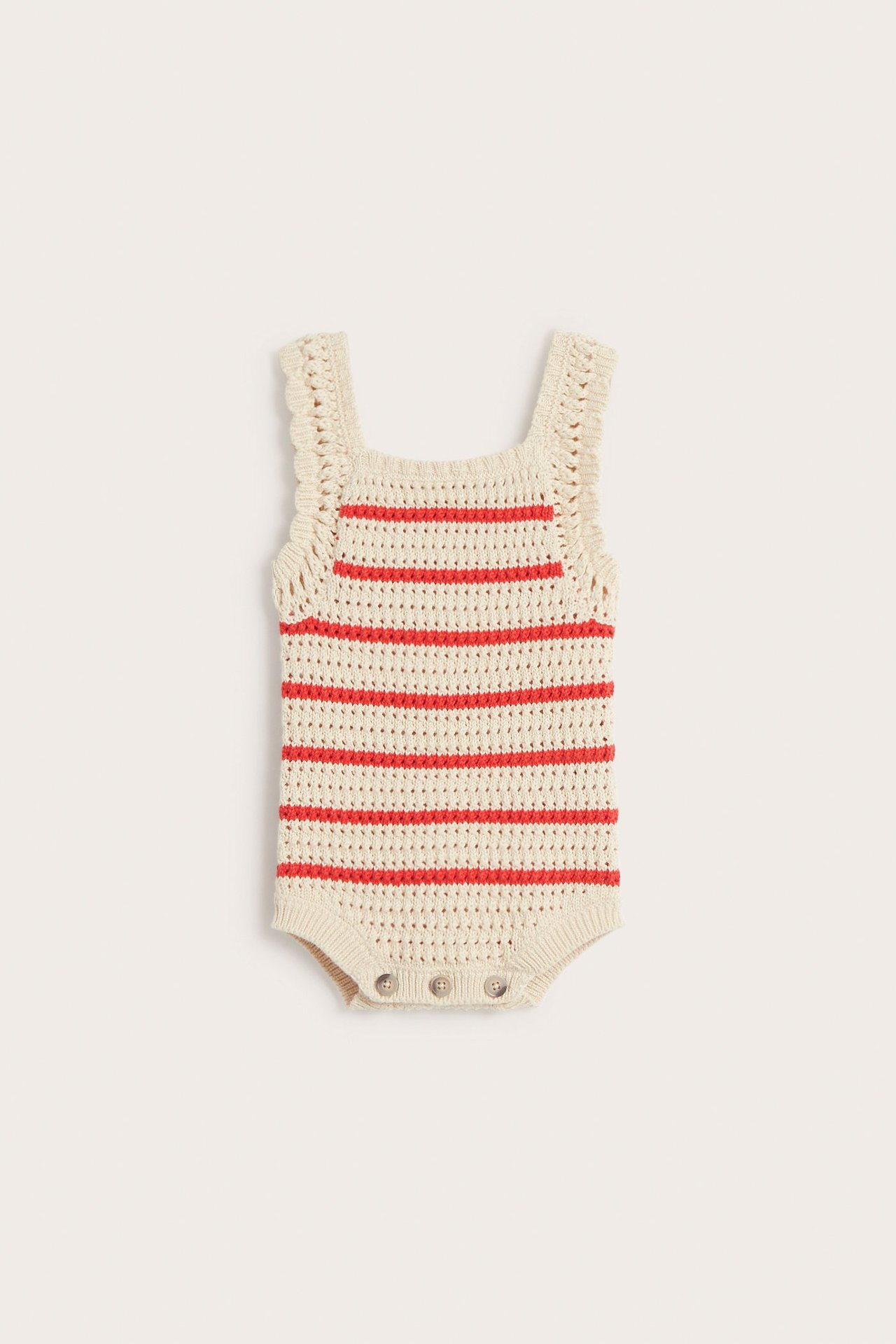 Edestä näkymä: Beige neulottu vauvan body punaisilla raidoilla ja neppareilla haarassa.