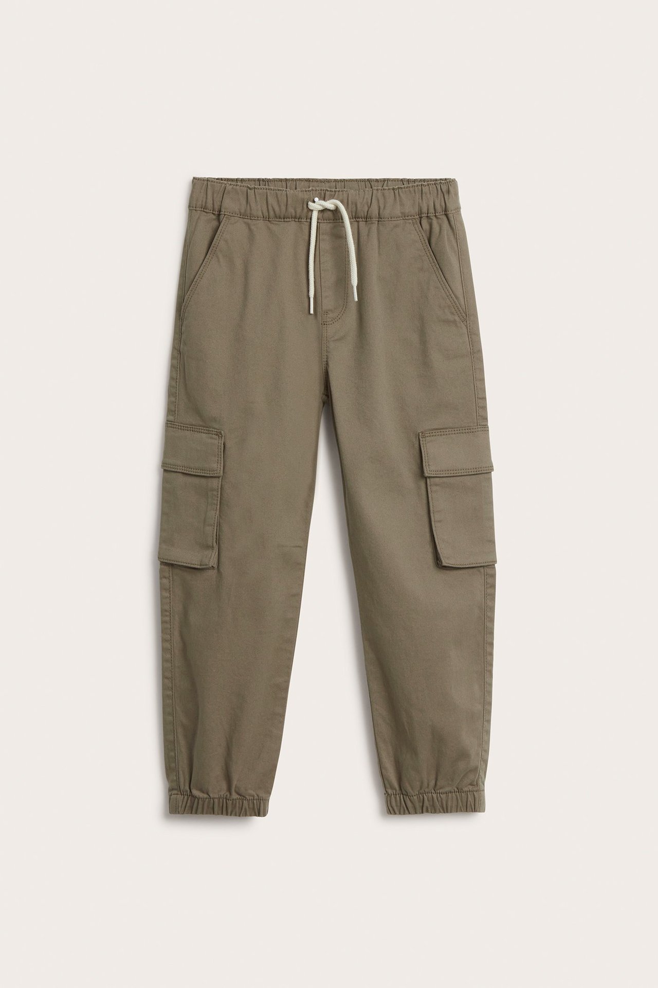 Frontvisning av brune cargobukser i bomull med elastisk midje, hvit snøring, sidelommer og mansjetter.
