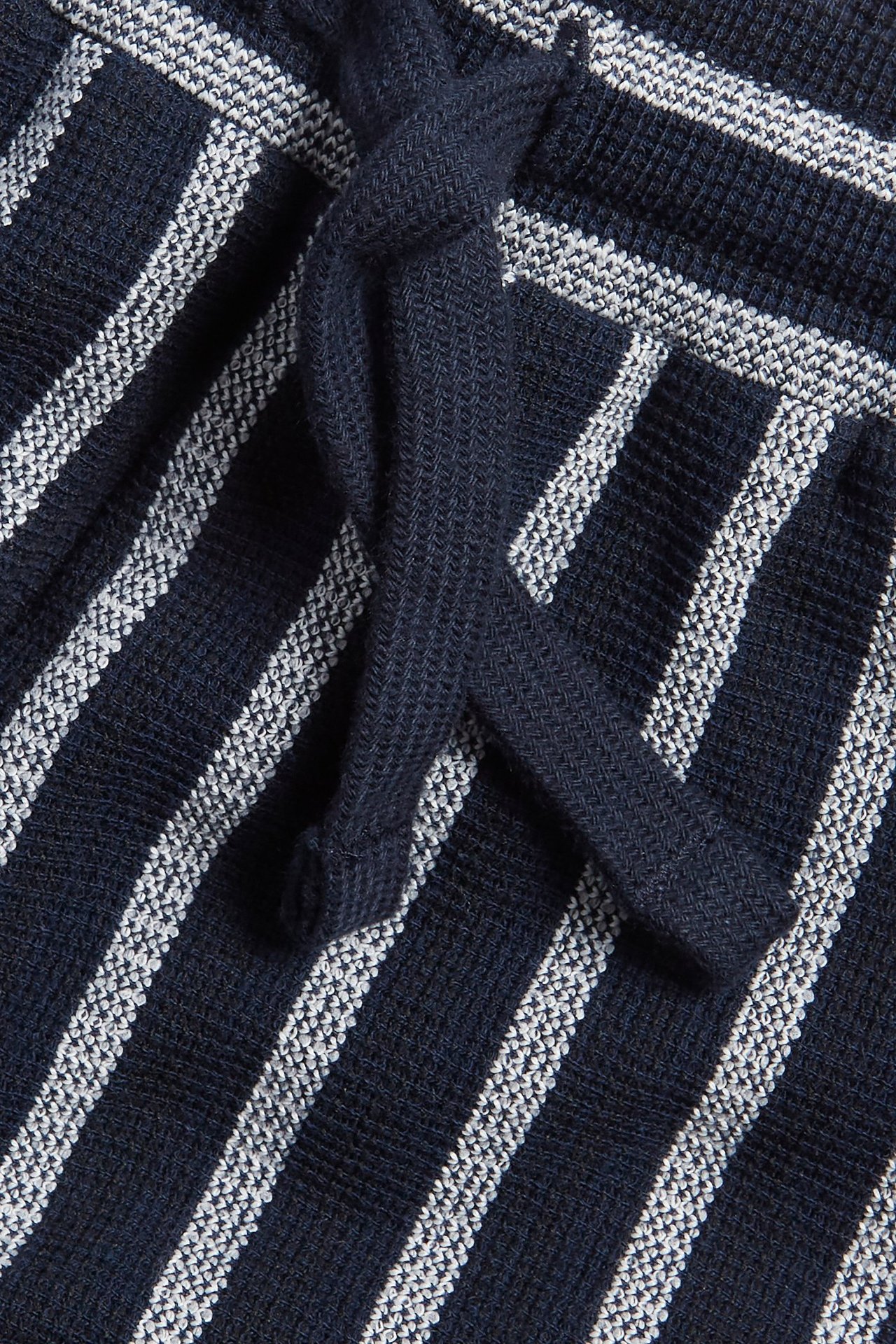 Zbliżenie na granatowe i białe szorty w paski z teksturowanej tkaniny z granatowym sznurkiem.