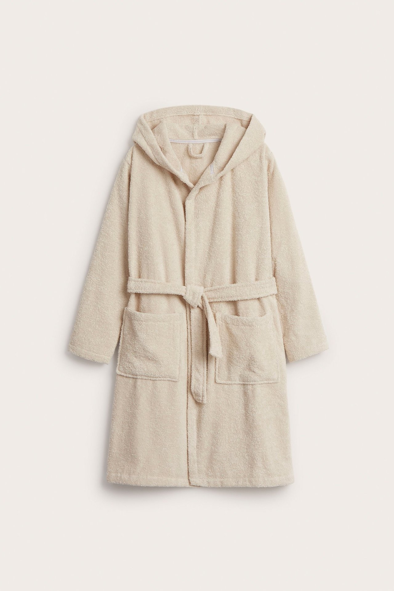 Edestä: beige froteinen hupullinen aamutakki solmittavalla vyöllä ja kahdella etutaskulla.