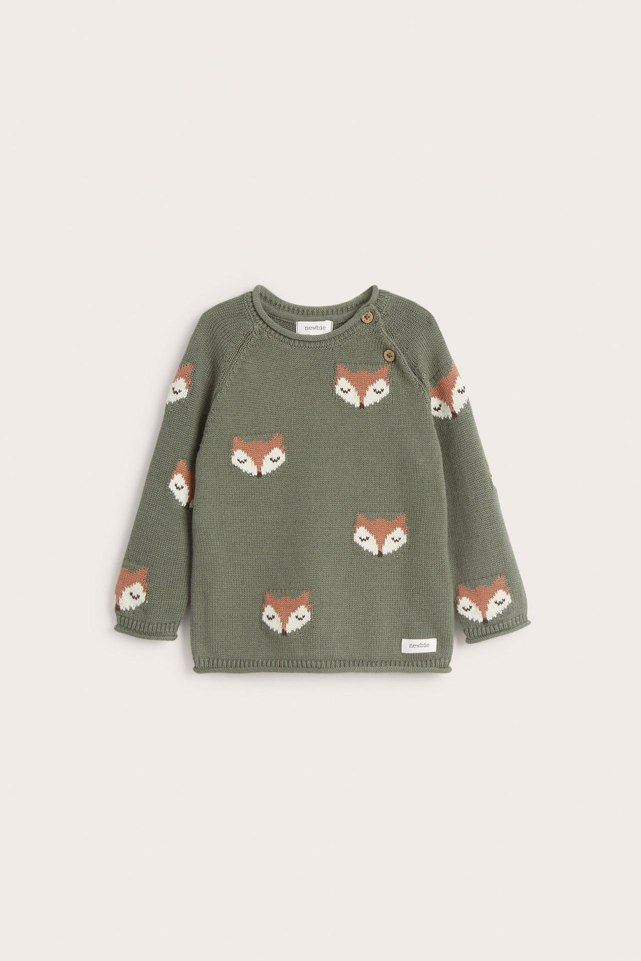 Edestä näkymä vauvan tummanvihreästä puuvillaneuleesta, jossa on jacquard-kudottu kettukuvio ja kaksi olkanappia.