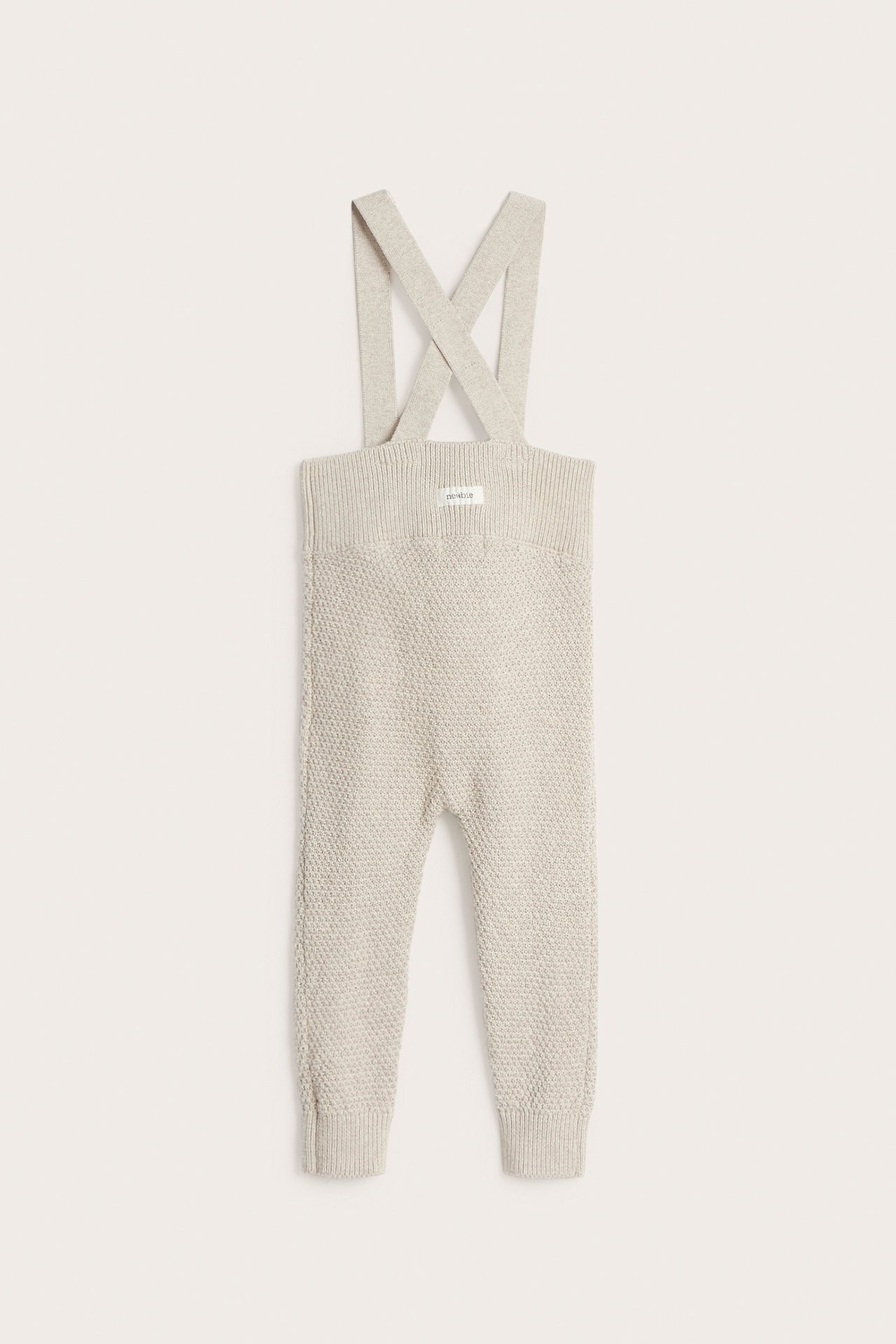 Edestä, beige melange -neuletyöhousut säädettävillä olkaimilla ja ribbiresoreilla.