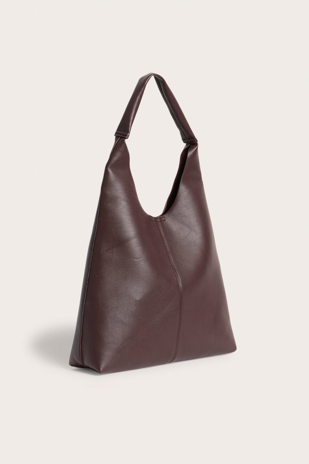 Framifrån, en enfärgad vinröd axelväska i mjukt skinnimitation med slouchig form.