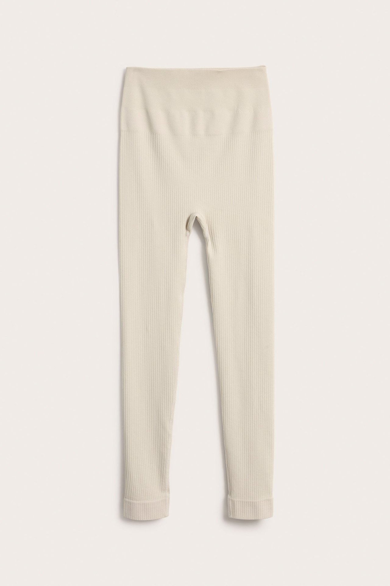 Edestä näkymä vaaleanbeigestä ribatusta saumattomasta treenileggingsistä, korkealla vyötäröllä.