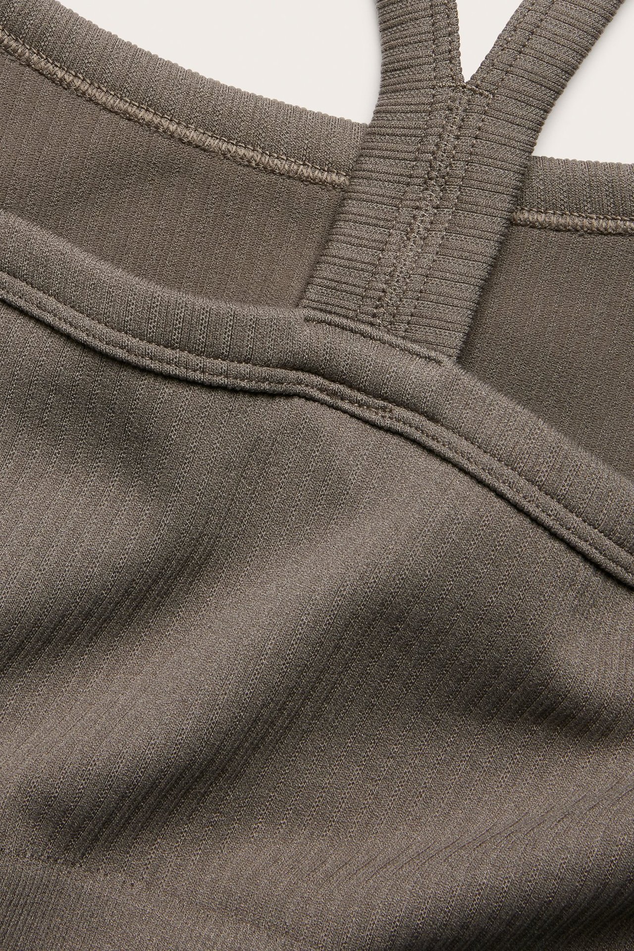 Zbliżenie brązowego, bezszwowego, prążkowanego biustonosza sportowego z szerokimi ramiączkami.