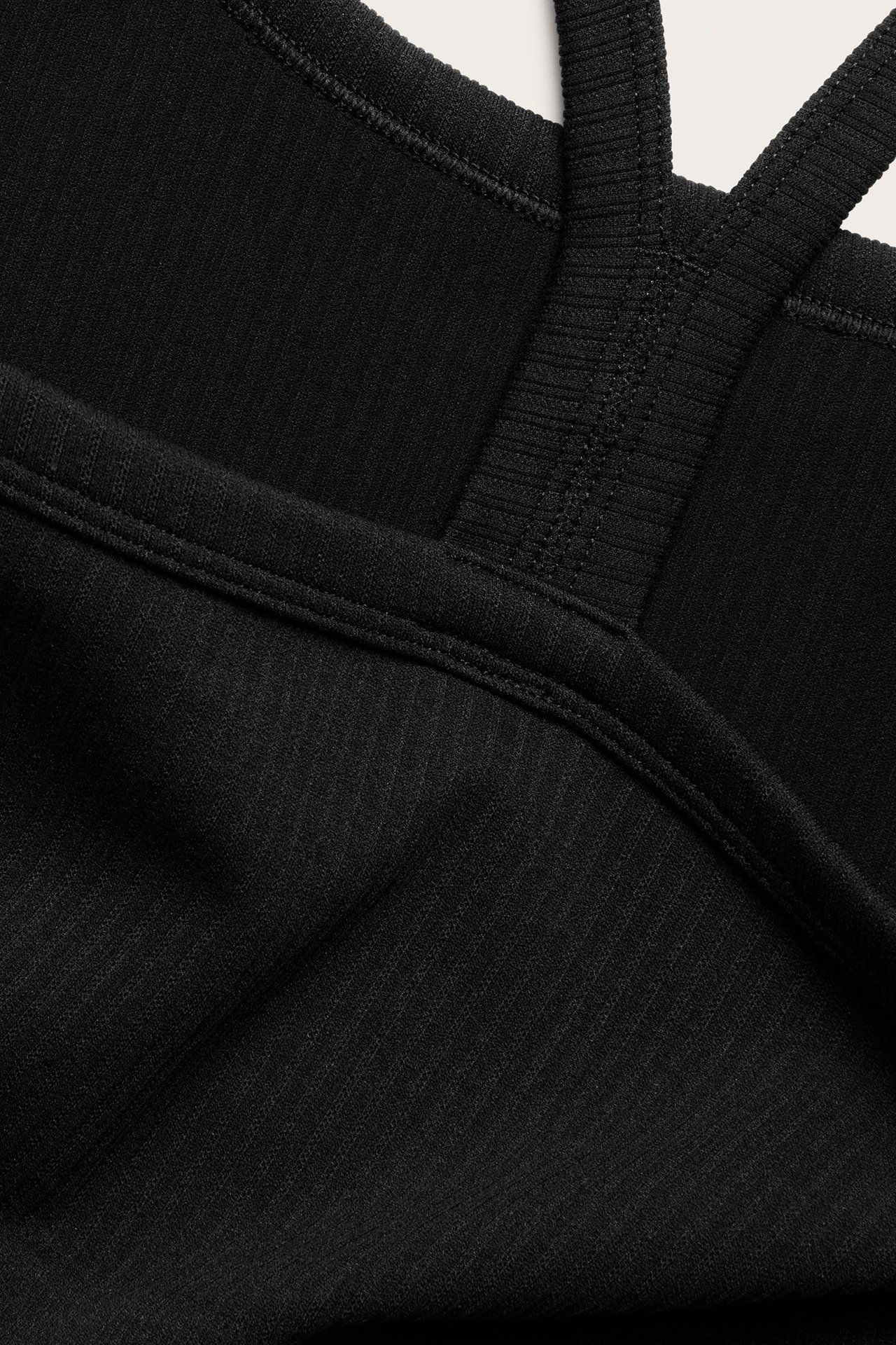 Zbliżenie czarnego, bezszwowego biustonosza sportowego z prążkowaną fakturą i szerokimi ramiączkami.