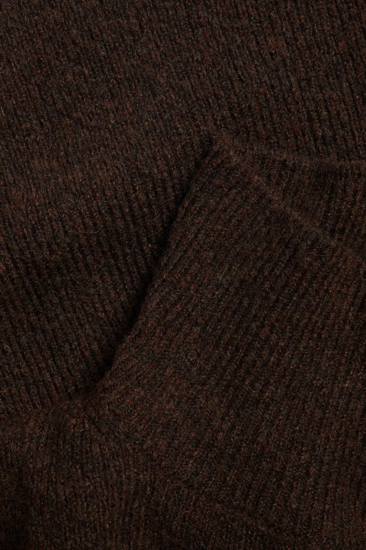 Zbliżenie na ciemnobrązowy melanżowy dzianinowy materiał, ukazujące jego prążkowaną teksturę.