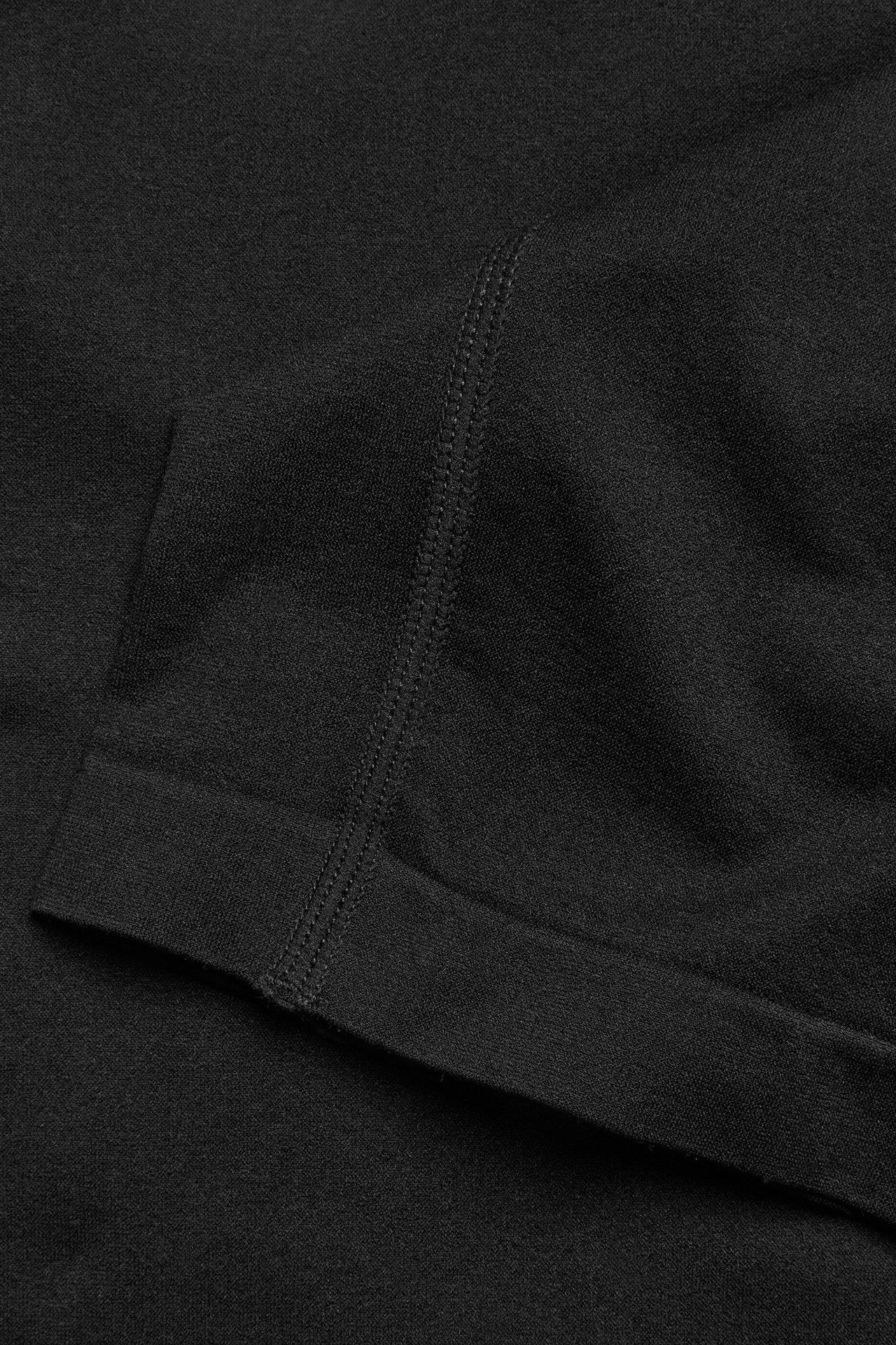 Zbliżenie czarnych bezszwowych szortów, ukazujące teksturę materiału i widoczny pionowy szew.