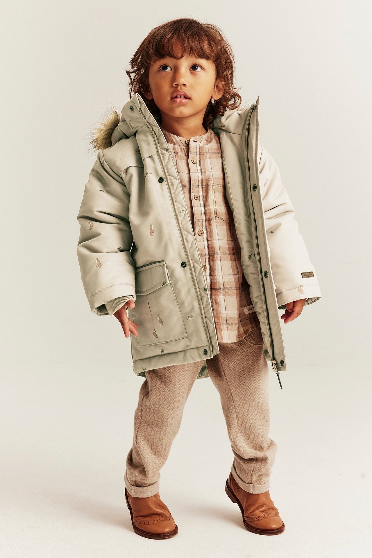Edestä: lapsi beigessä kettutakissa, ruutupaita, ruskeat housut ja brogue-kengät.