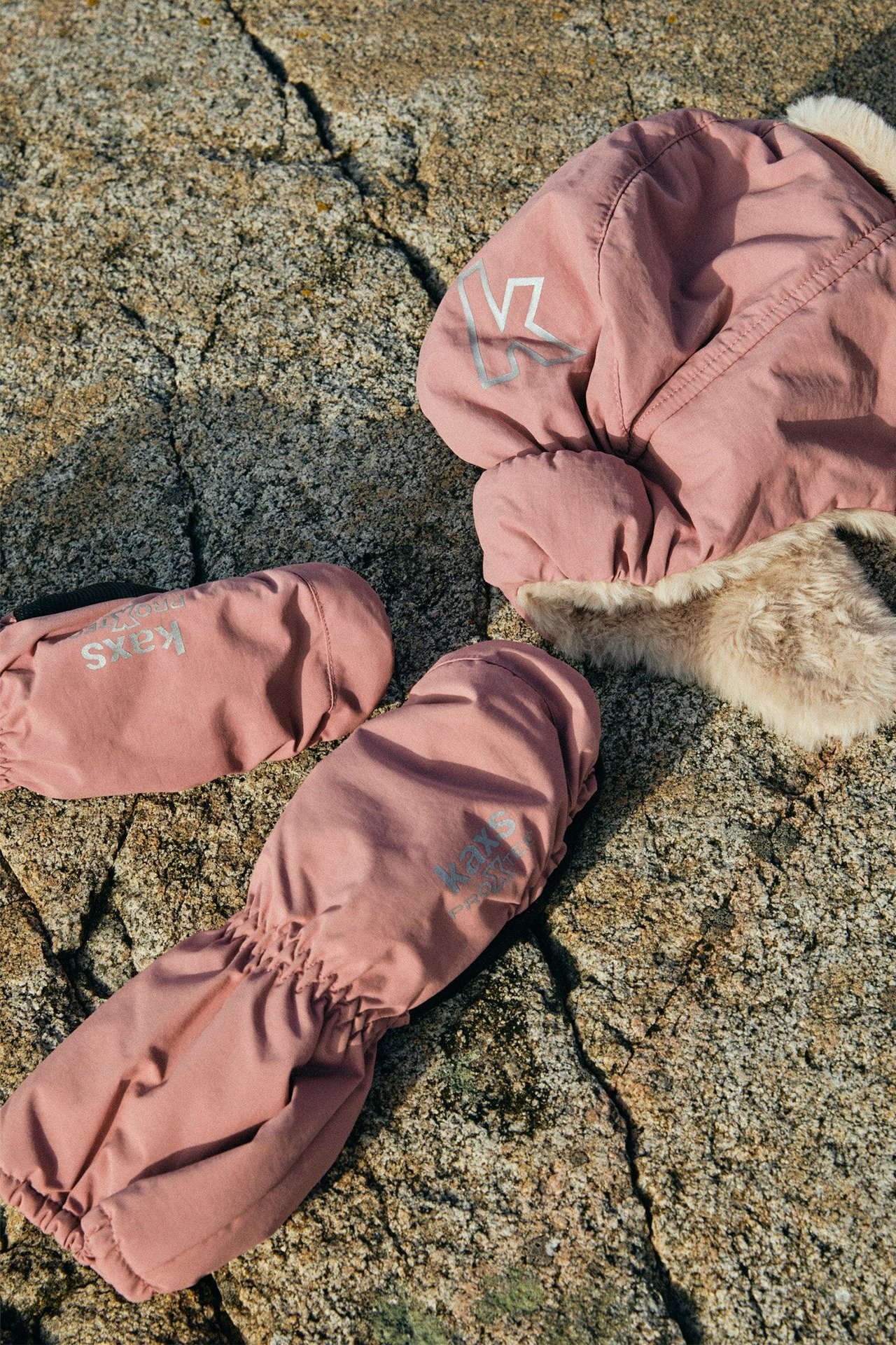 Ylhäältä näkymä pinkeistä lasten rukkasista joustavilla rannekeilla ja pinkistä tekoturkishatusta.