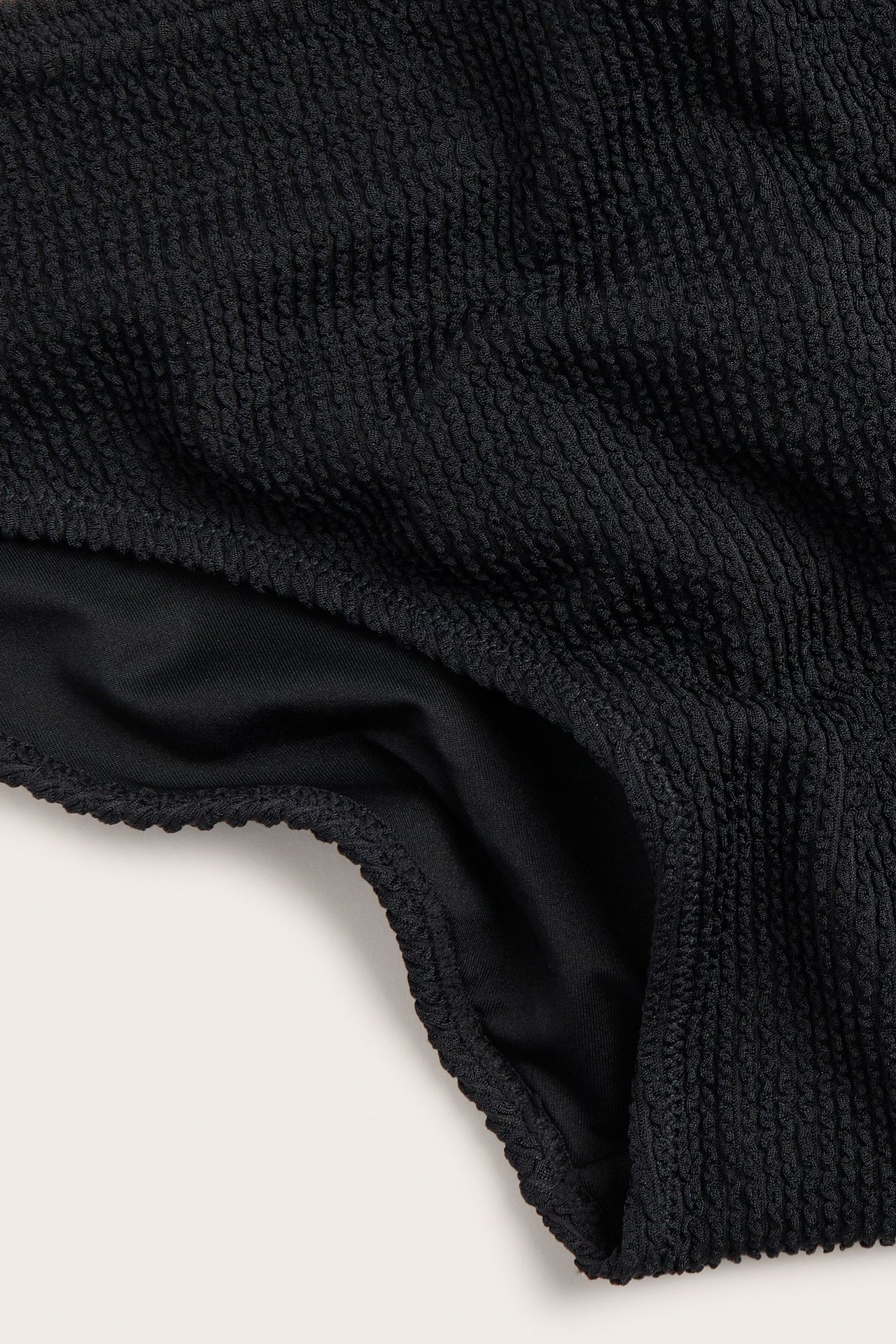 Zbliżenie na czarne, teksturowane figi kąpielowe typu brief.