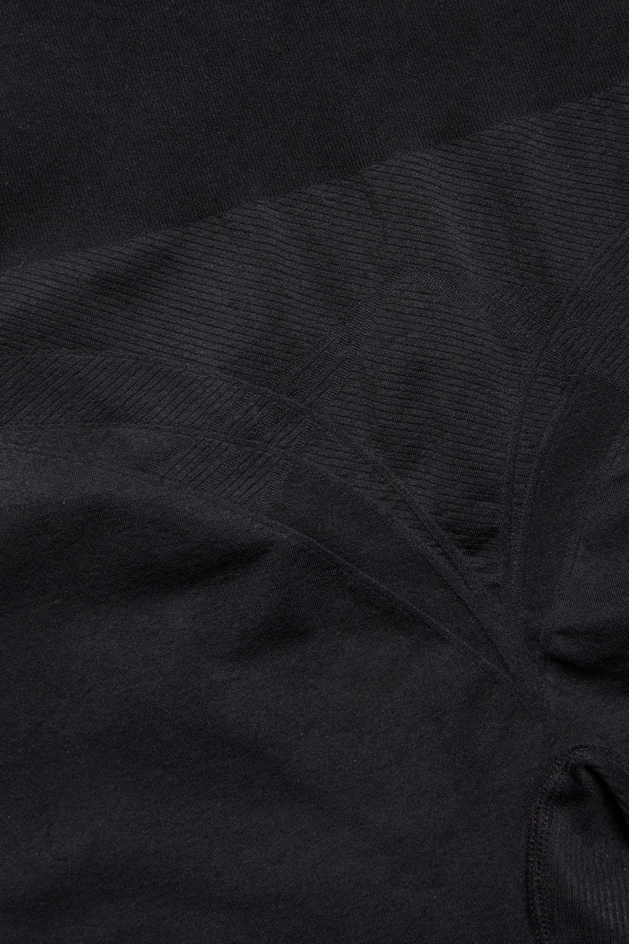 Zbliżenie czarnych, bezszwowych szortów modelujących z wysokim stanem i subtelnymi prążkowanymi detalami.