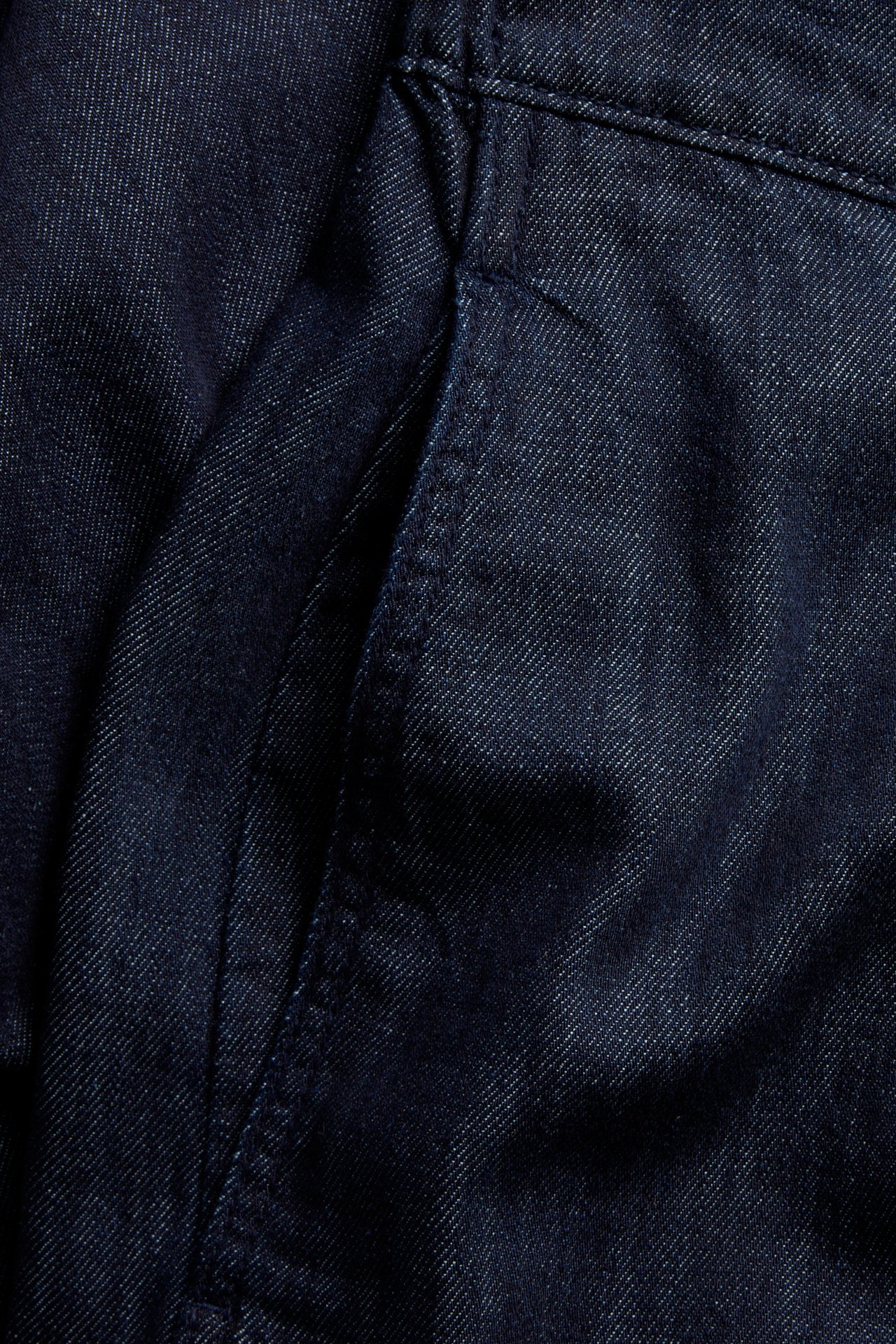 Zbliżenie na ciemne dżinsy pull-on, ukazujące boczną kieszeń i widoczne szwy.