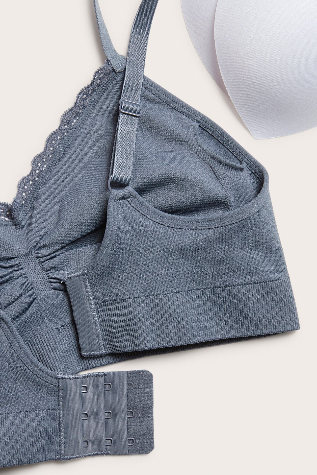 Zbliżenie na granatowy bezszwowy biustonosz bez fiszbin z koronkowym wykończeniem, regulowanymi ramiączkami, zapięciem na haftki i wyjmowanymi wkładkami.