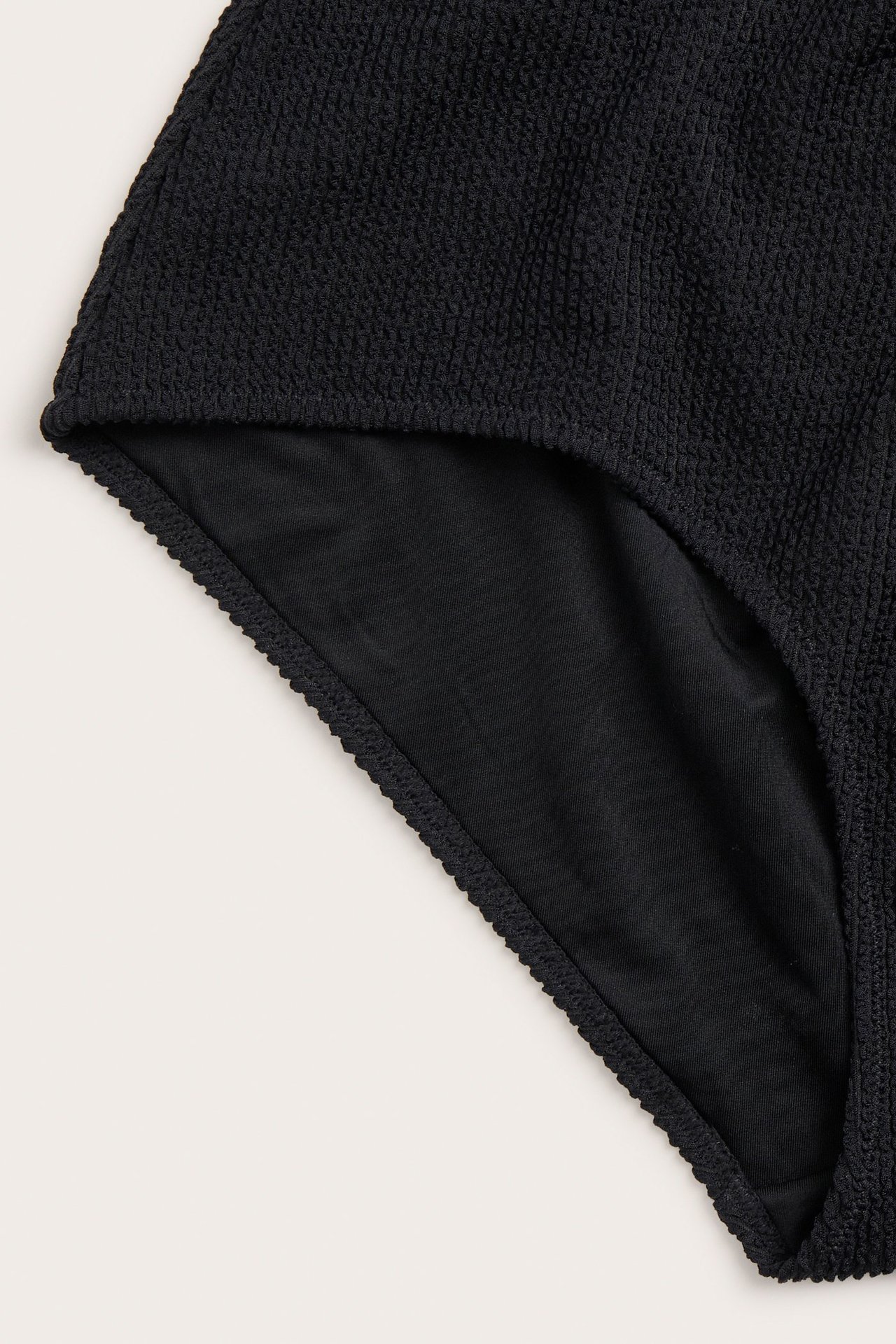 Zbliżenie czarnych, wysokich majtek kąpielowych typu hipster z teksturowanej tkaniny.