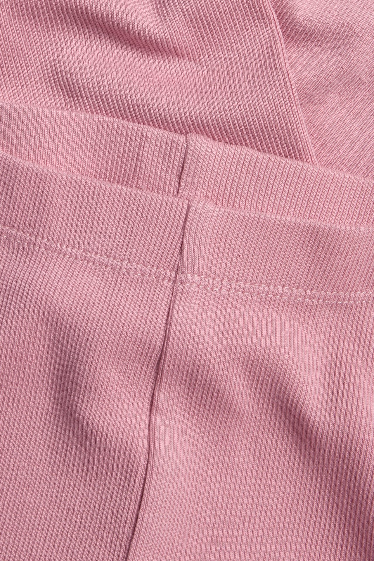 Lähikuva vaaleanpunaisista ribbineuleleggingseistä näkyvillä saumoilla.
