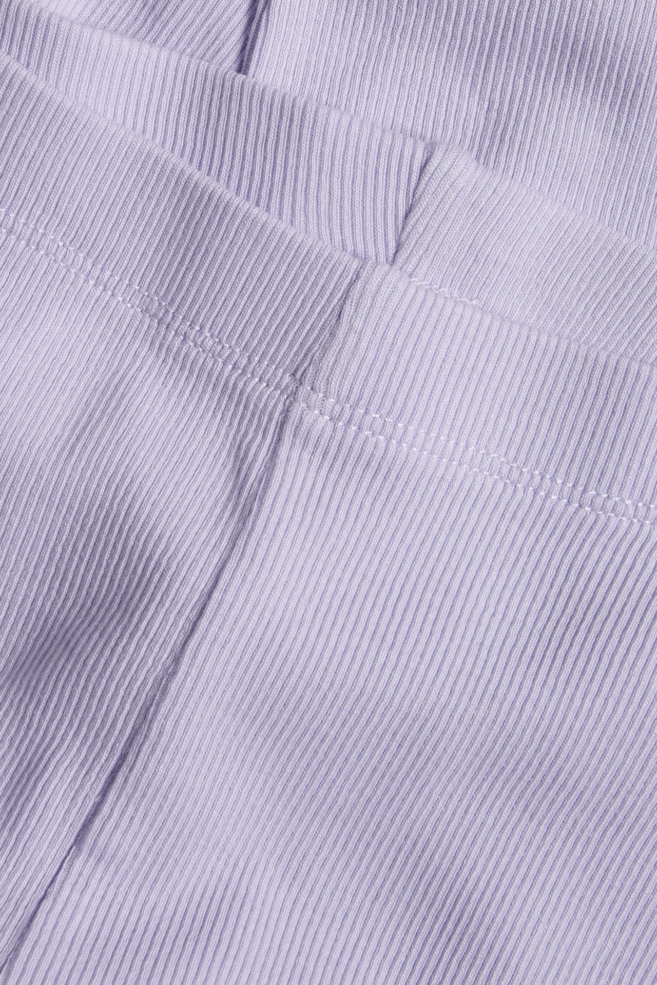 Zbliżenie na jasnofioletowe prążkowane legginsy.