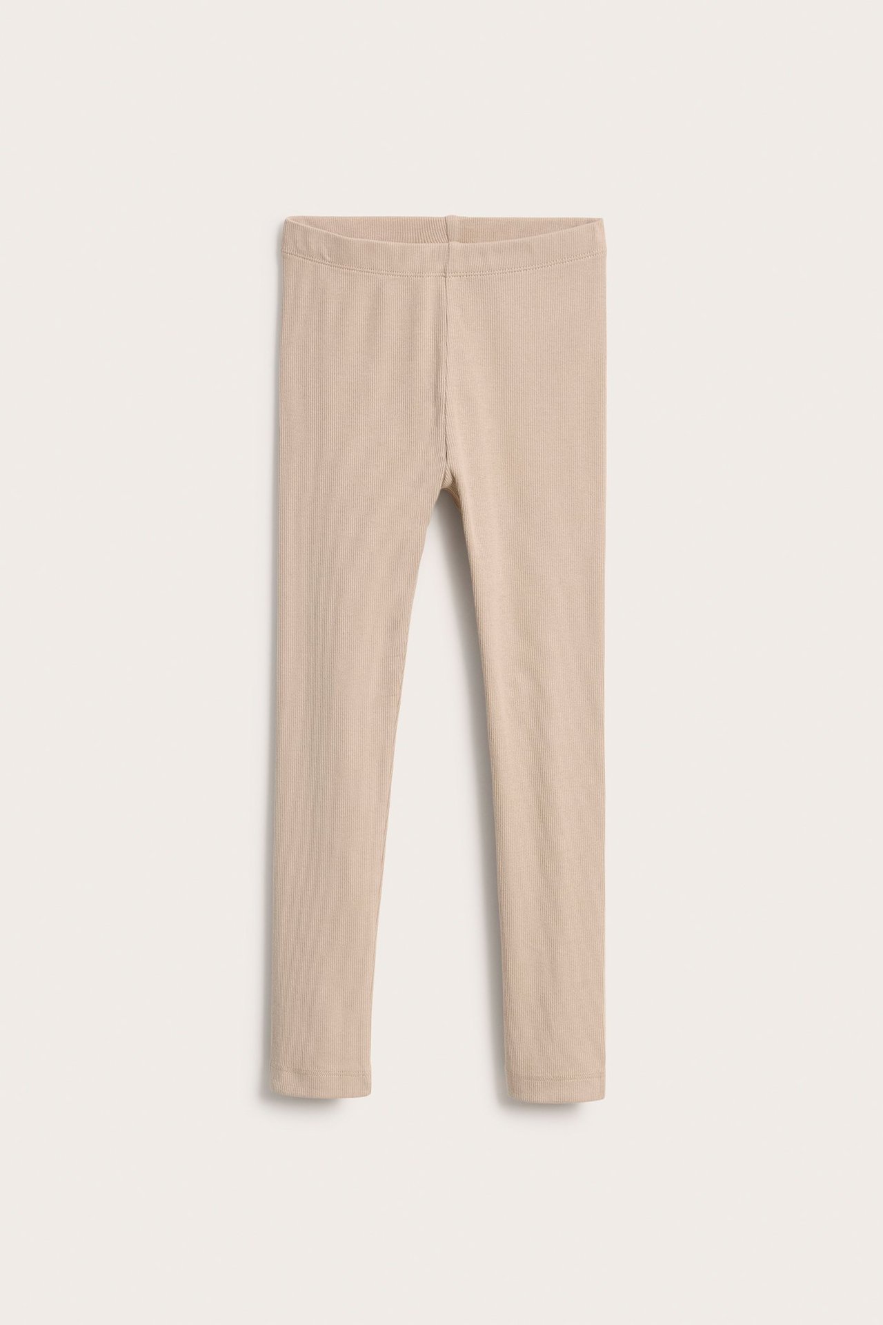 Edestä näkymä beigestä ribbineulotusta lasten leggingseistä joustavalla vyötäröllä.