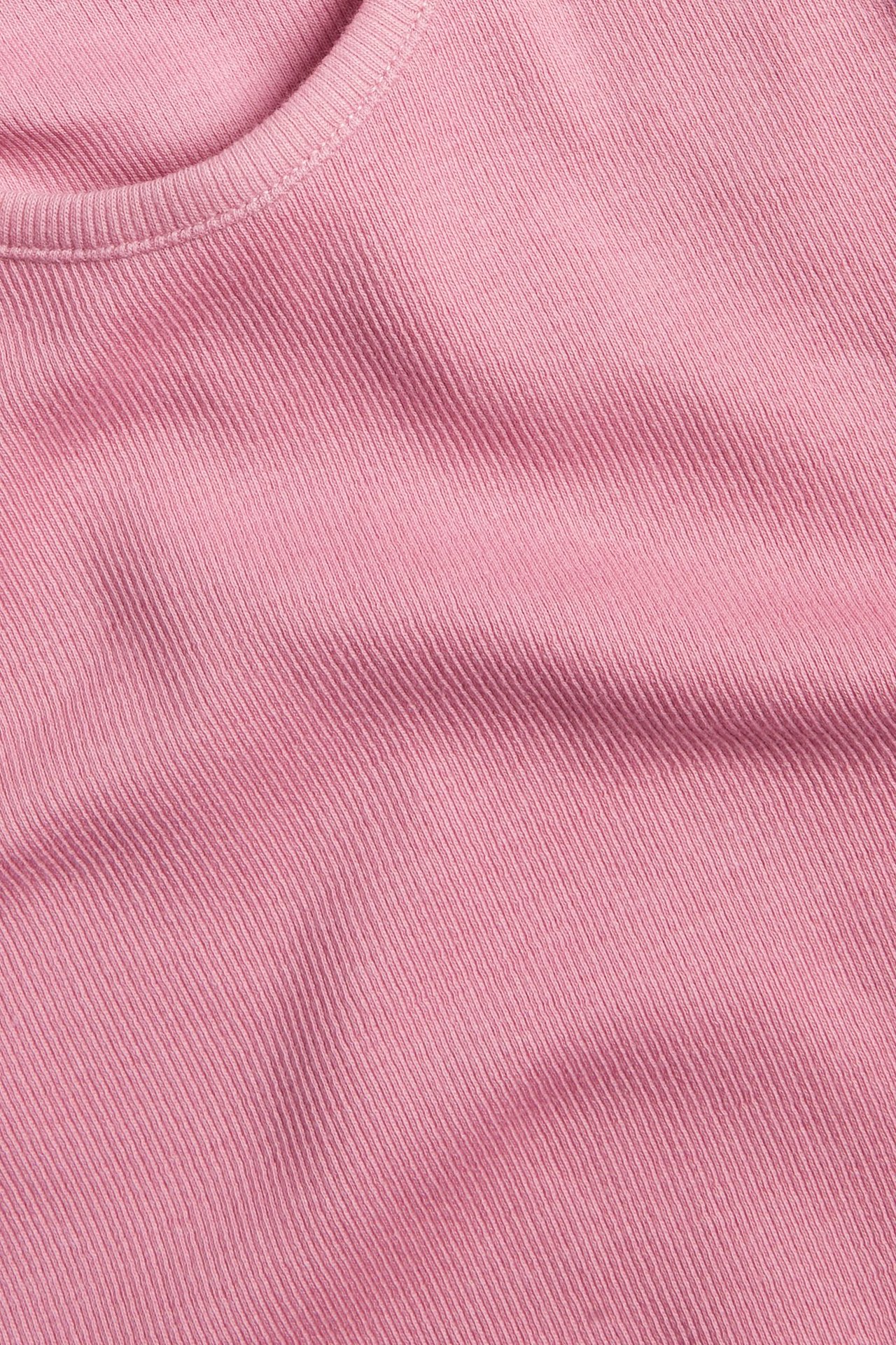 Zbliżenie różowego, prążkowanego topu z krótkim rękawem i widocznym dekoltem.