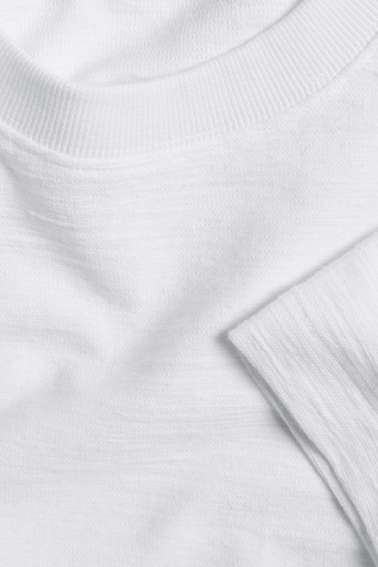 Zbliżenie białego, teksturowanego bawełnianego T-shirtu z prążkowanym okrągłym dekoltem.
