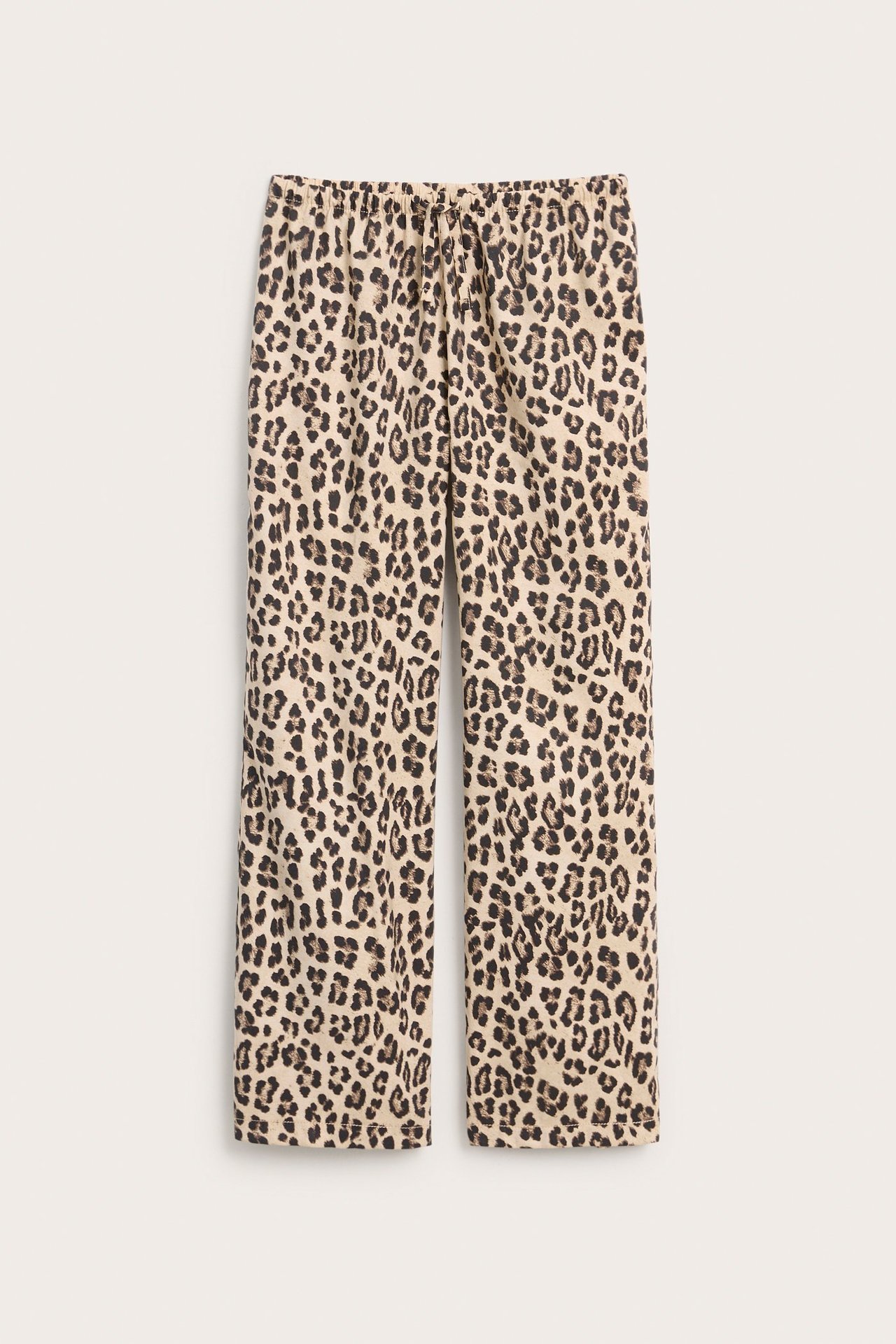 Widok z przodu: luźne brązowe spodnie dziecięce w panterkę z elastyczną talią i sznurkiem.