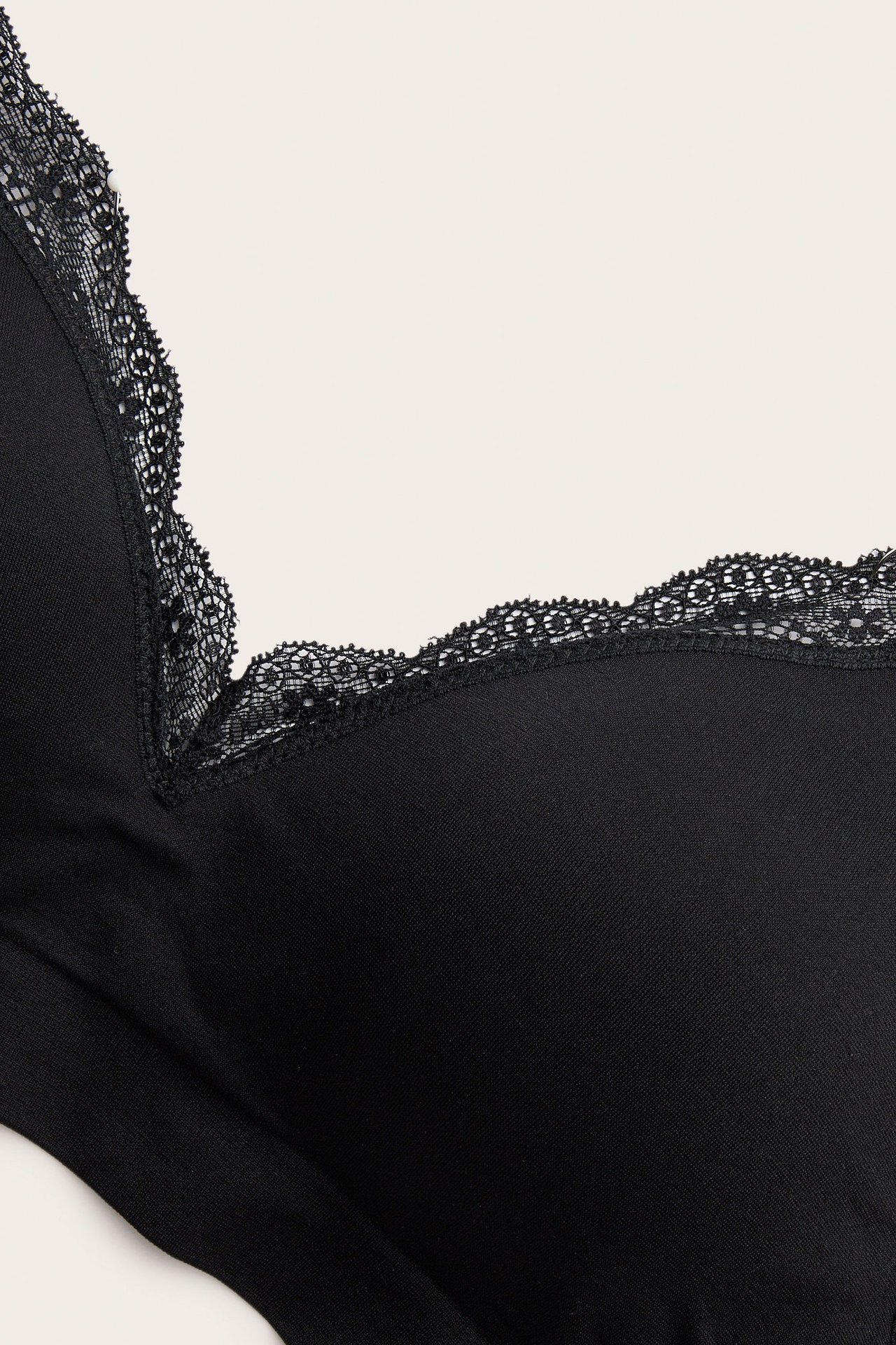 Zbliżenie czarnego, miękkiego, bezszwowego biustonosza z formowanymi miseczkami i koronkową lamówką.