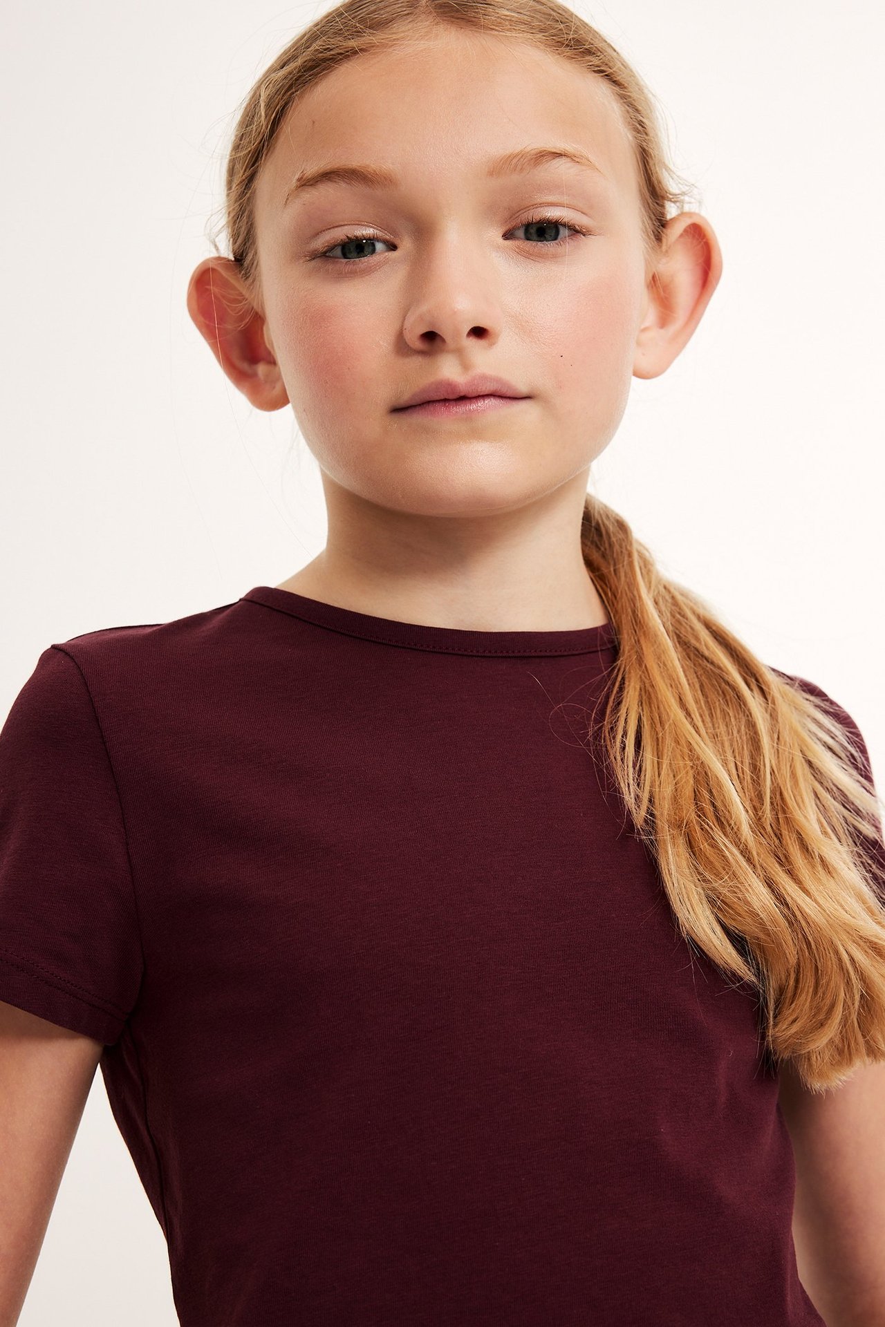 Barnkille i mörkröd enfärgad T-shirt i bomull, frontvy.