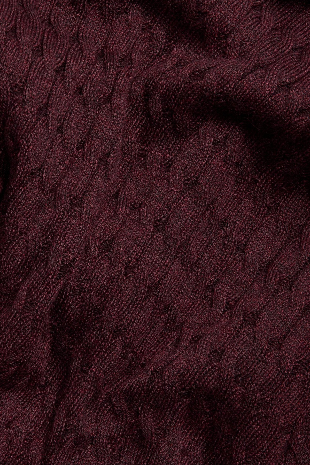 Zbliżenie na bordowy melanżowy materiał swetra o warkoczowym splocie.