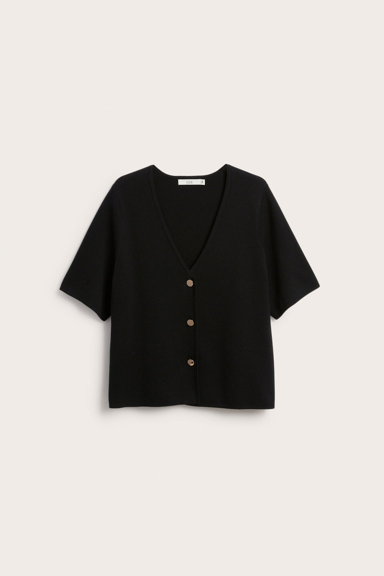 Framifrån: svart kortärmad kofta med v-ringning och tre guldiga metallknappar.