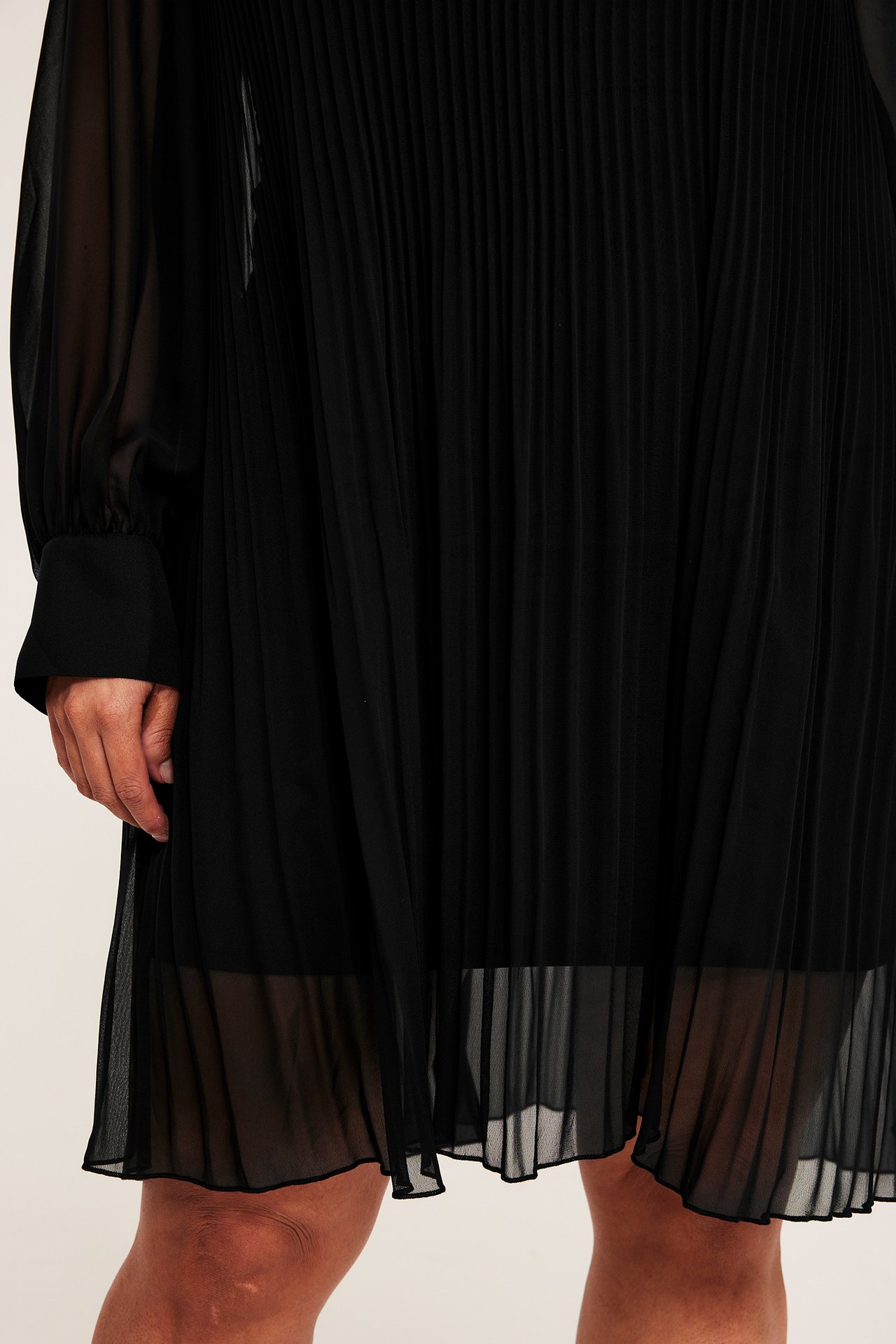 Svart A-linje plisseret chiffon kjole, kneilengde, rund hals, lang erme, enfarget.