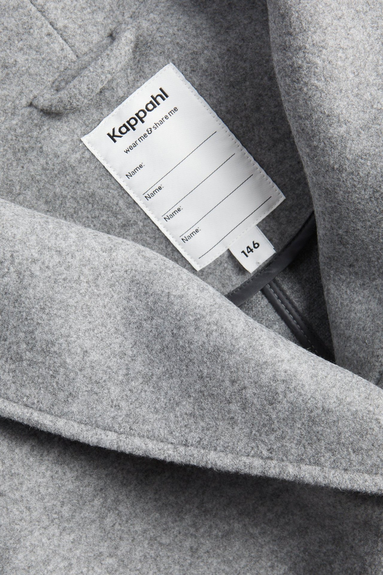 Zbliżenie jasnoszarej melanżowej kurtki poliestrowej, ukazujące fakturę materiału i białą wewnętrzną metkę.