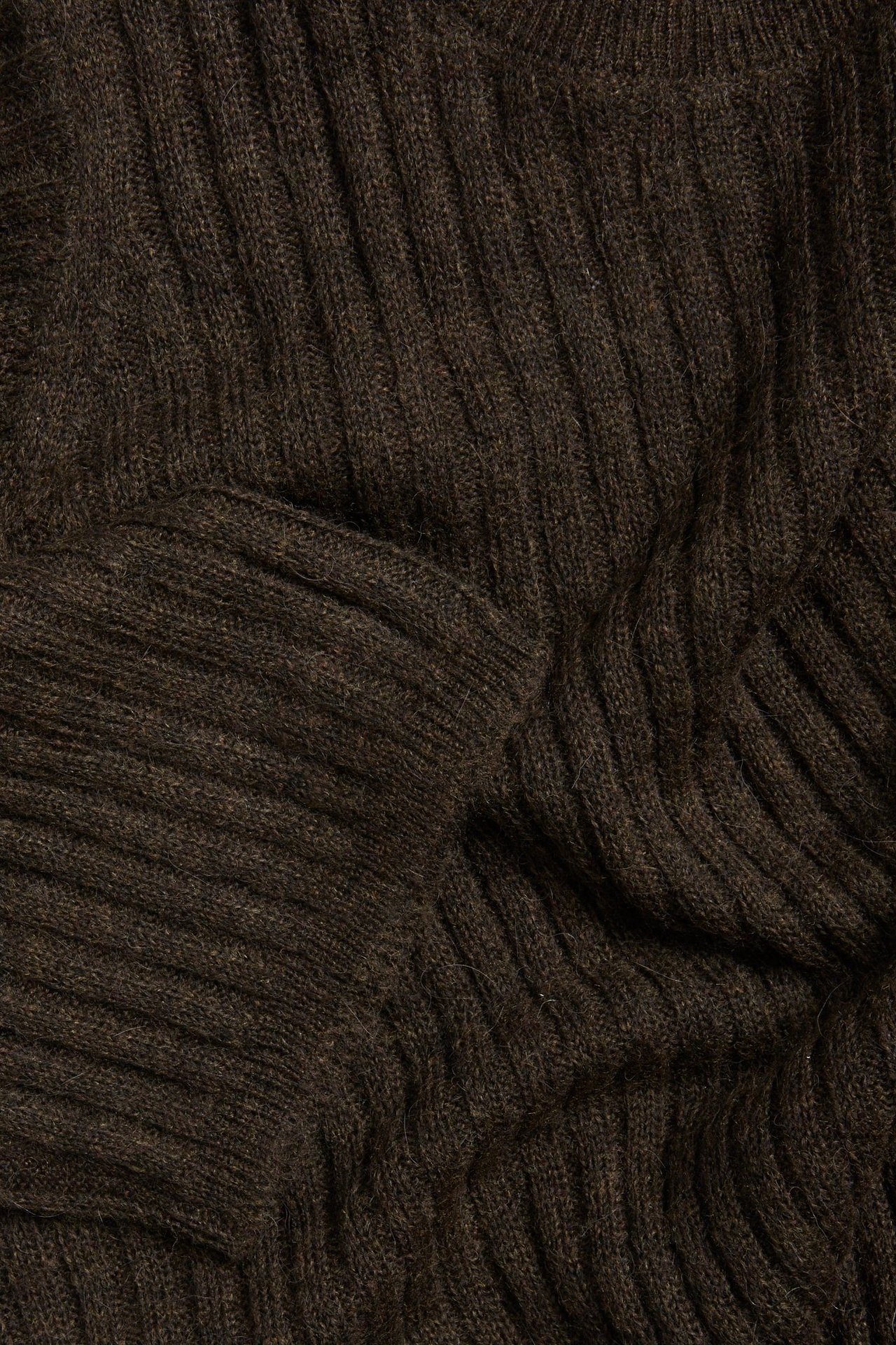 Zbliżenie na ciemnobrązowy melanżowy prążkowany materiał swetra z krótkim rękawem.