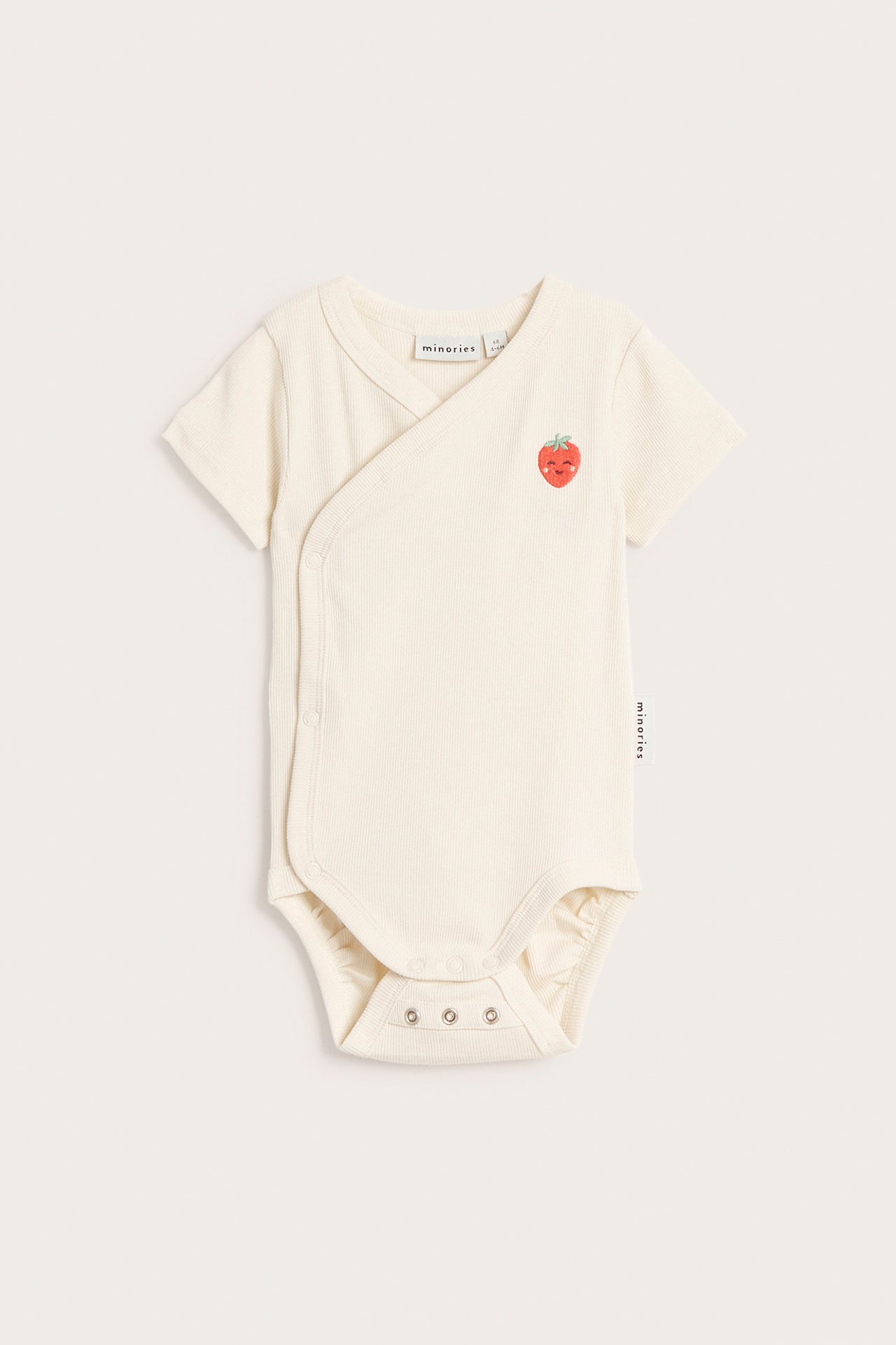 Edestä: Vaalea beige ribattu vauvan body, jossa kietaisumalli, nepparit ja mansikkakirjailu.