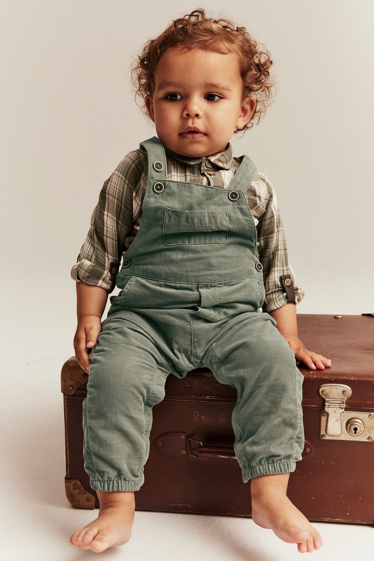 Lapsi tummanvihreissä Manchester-hängslepukissa, napit, taskut ja resori, etunäkymä.