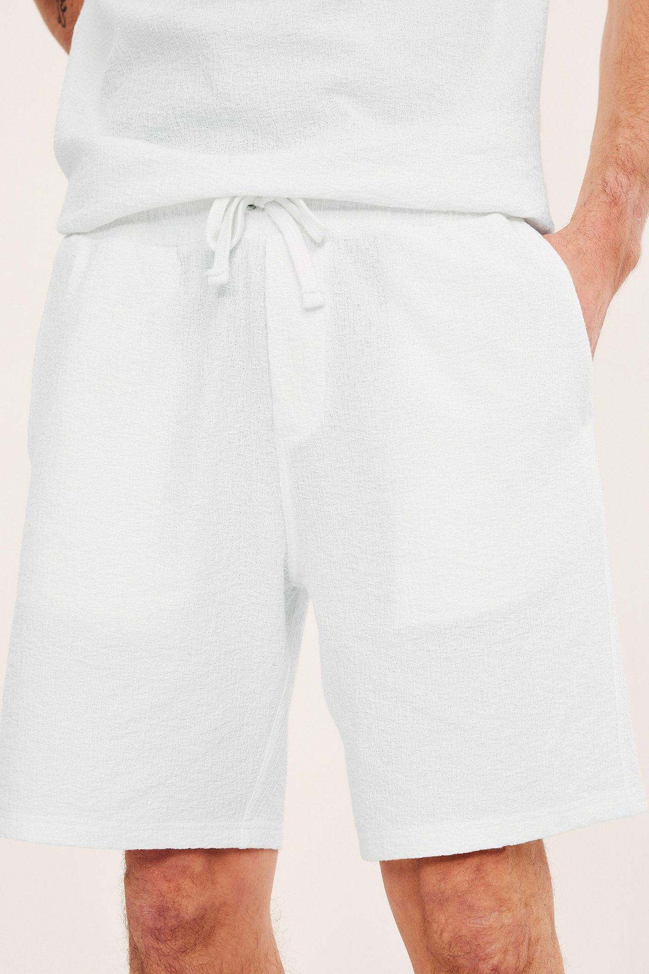 Edestä, mies yllään luonnonvalkoiset kuvioidut shortsit kiristysnyörillä ja yhteensopiva t-paita.