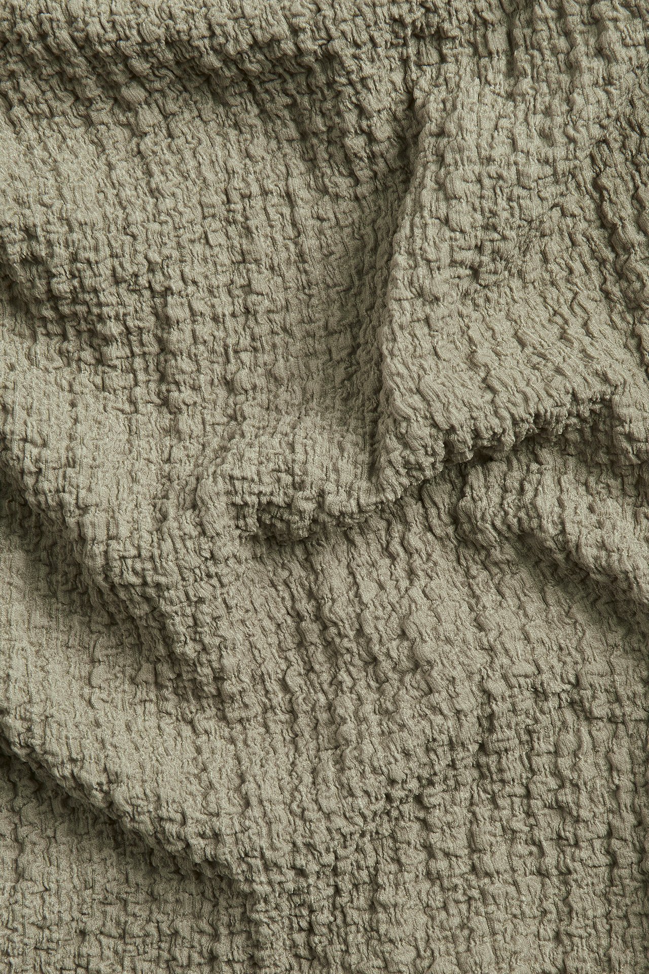 Närbild av grönt polyester-elastan tyg med en texturerad bubbelstruktur.