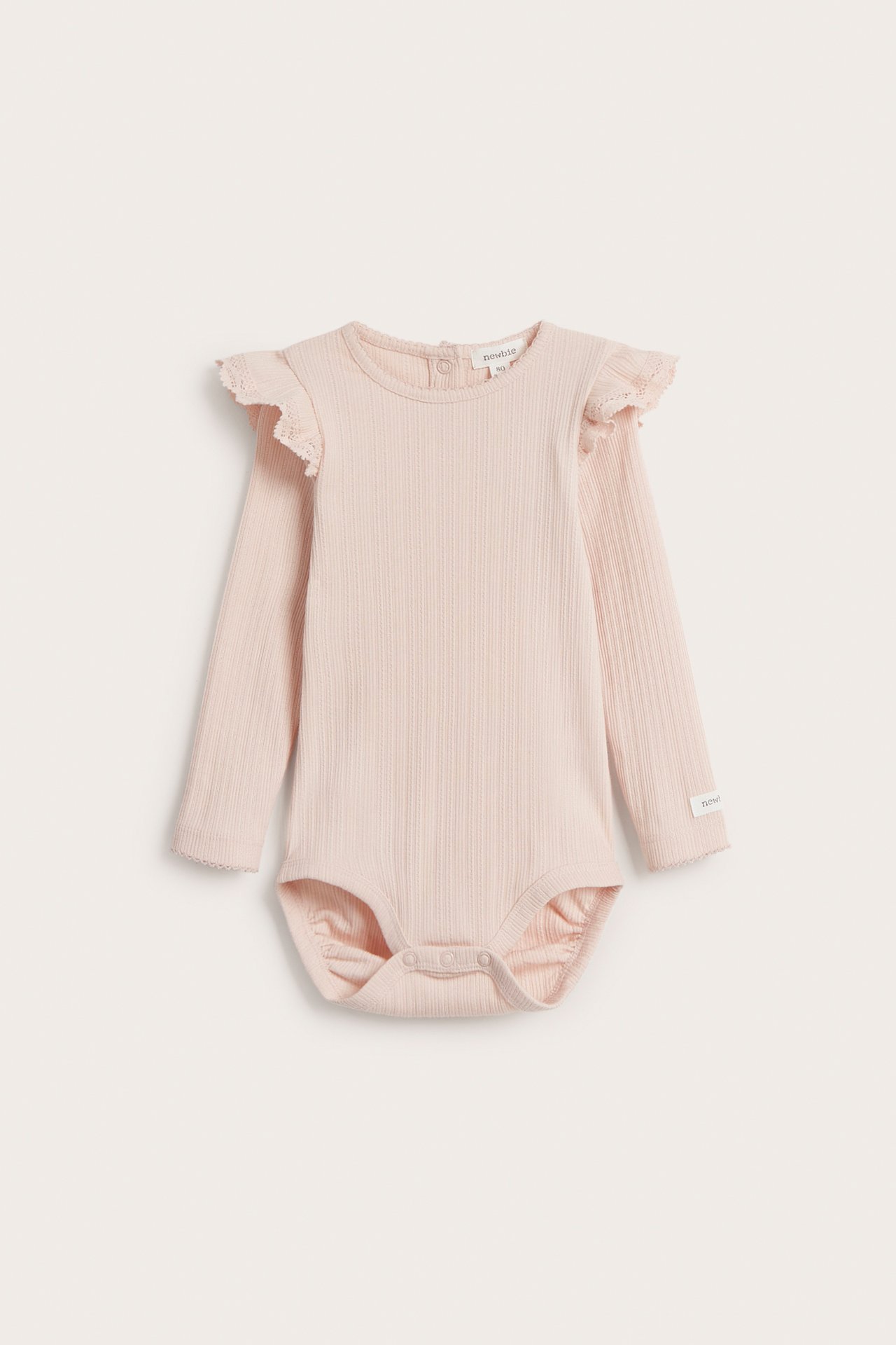 Frontvy av en ljusrosa ribbad babybody med långa ärmar, volanger på axlarna och tryckknappar.