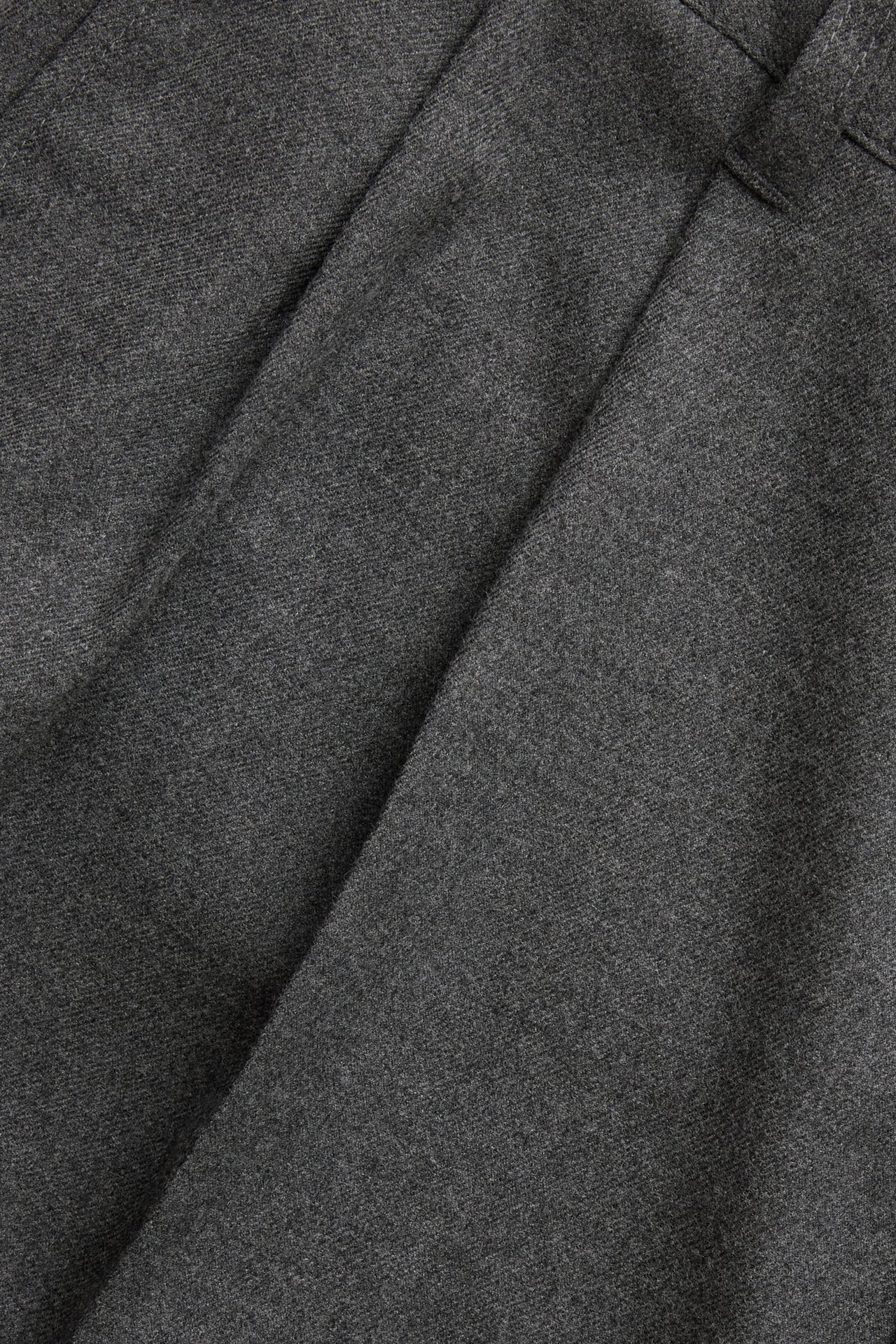 Zbliżenie szarych melanżowych spodni garniturowych z podwójnymi zakładkami z przodu.