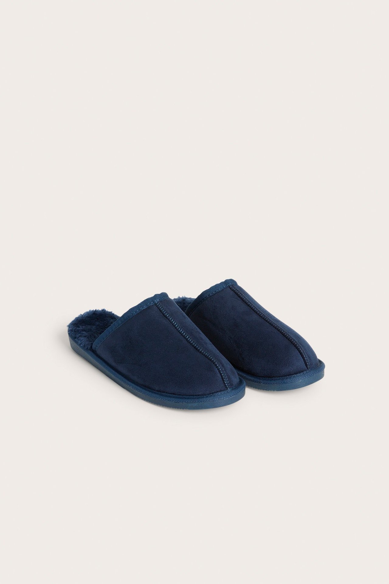 Widok z przodu pary ciemnoniebieskich wsuwanych kapci z imitacji zamszu z futerkiem.