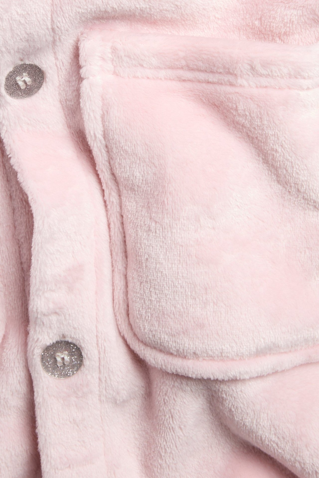 Zbliżenie różowego szlafroka polarowego z dwoma brokatowymi guzikami i naszywaną kieszenią.