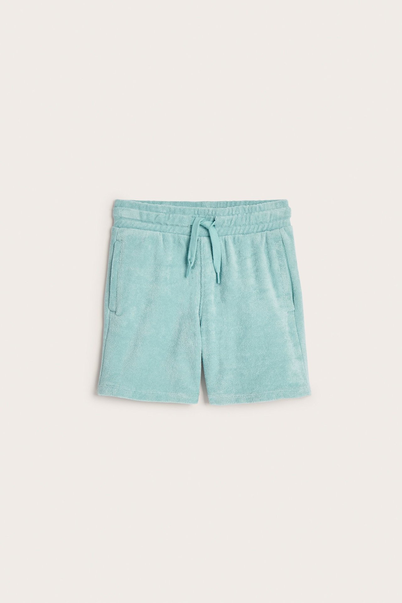 Framifrån, ljusgröna frottéshorts med resår i midjan och dragsko.